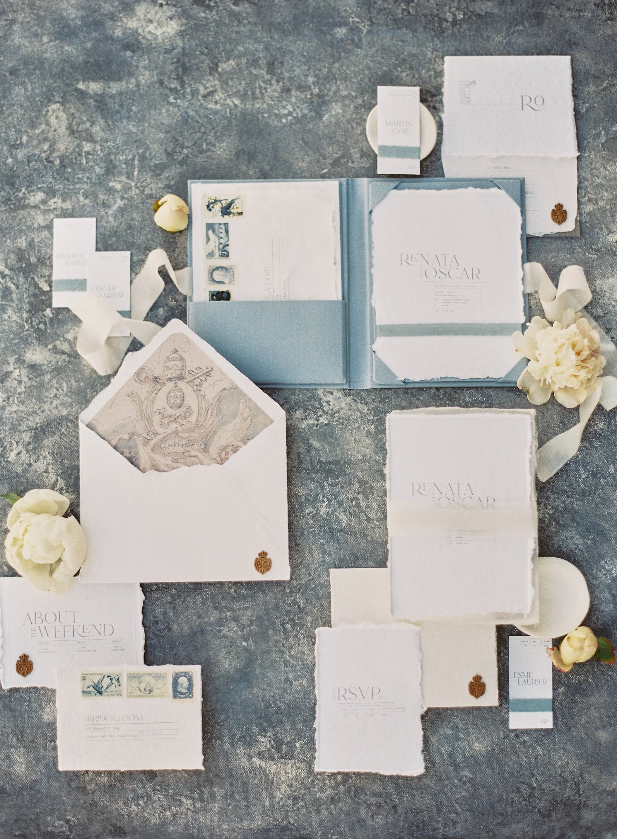 editorial wedding invitation suite with deckle-edge stationery and dusty blue accents on a hand-painted styling surface