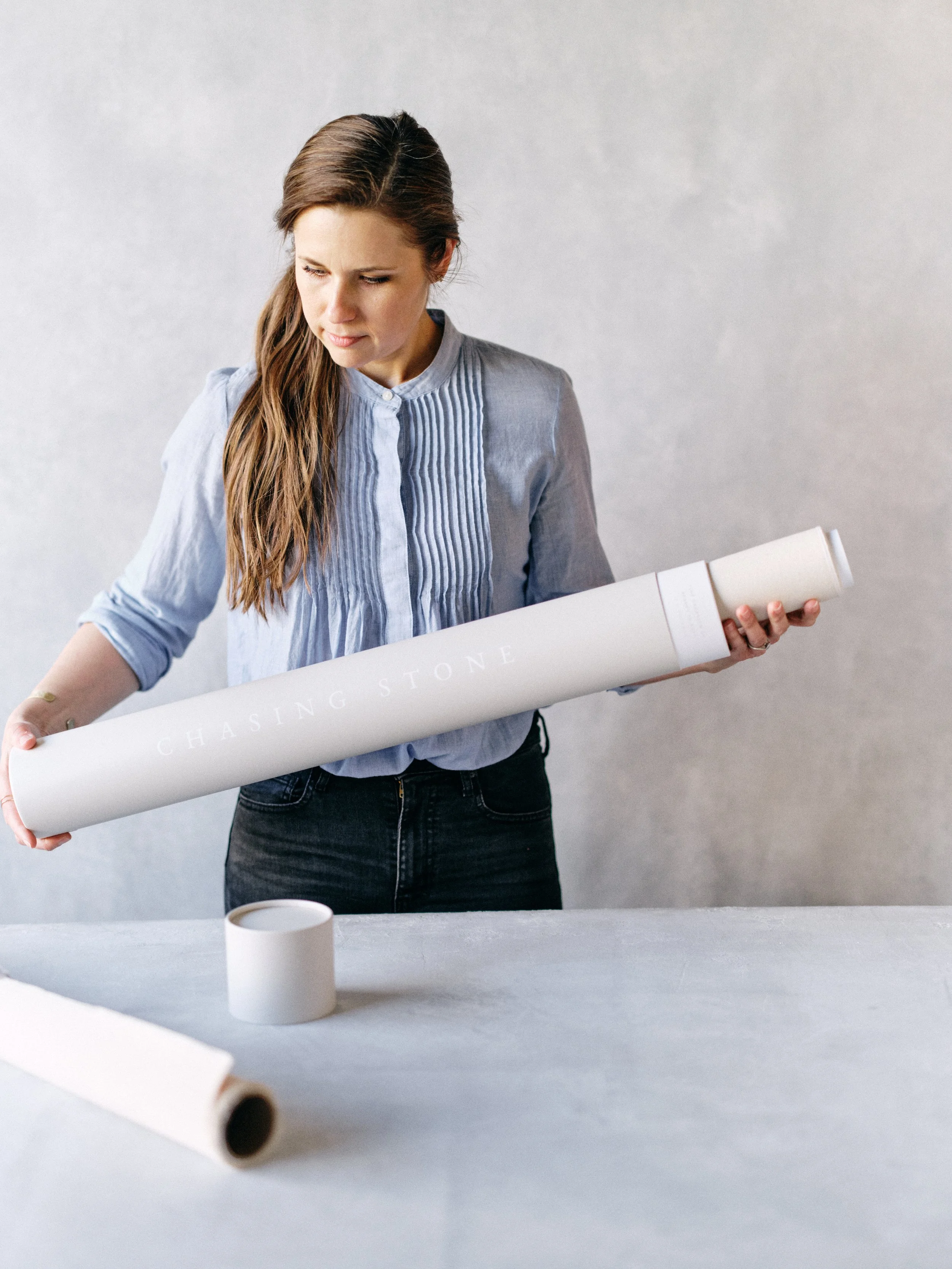 woman holding rolled hand-painted canvas backdrop for proper storage in a photography studio
