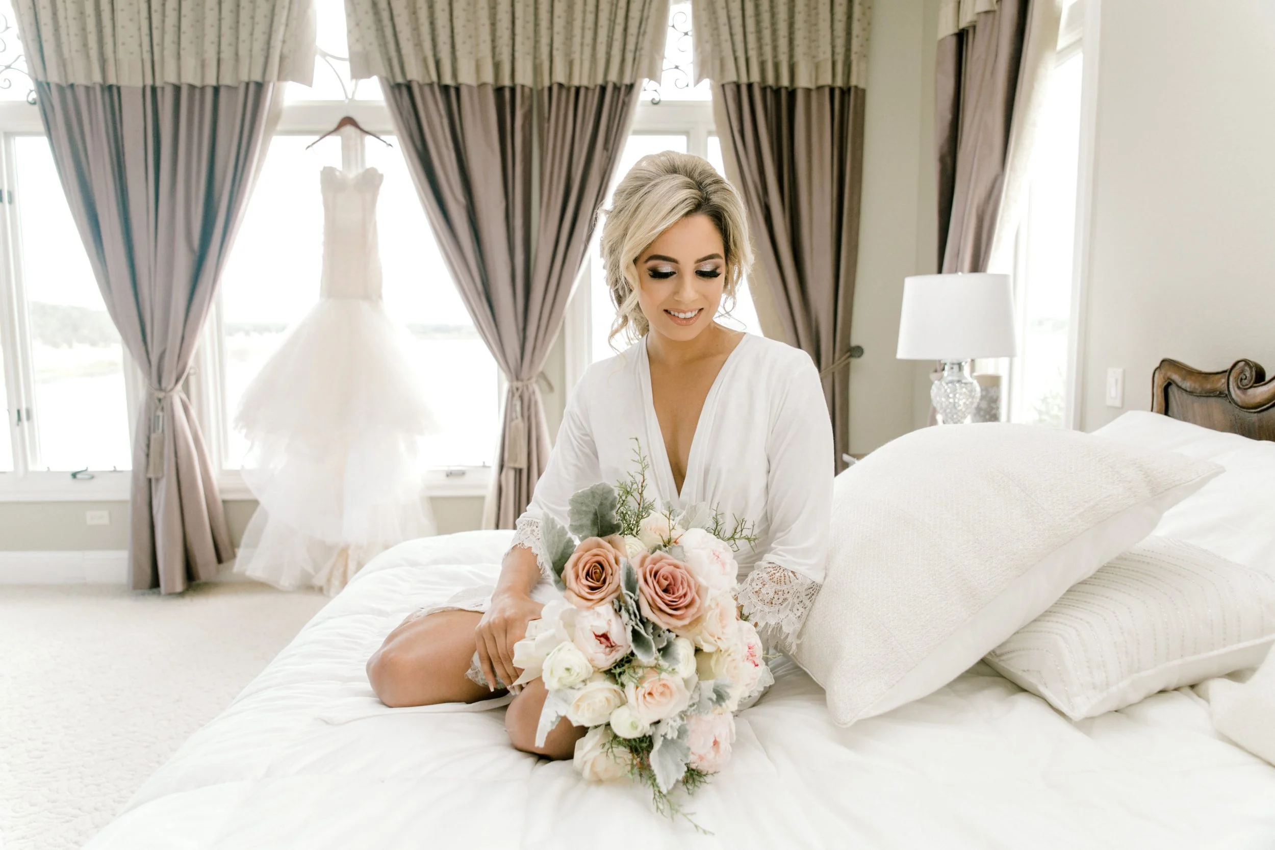 Bride white robe blush bouquet wedding dress hanging window getting ready photography natural light