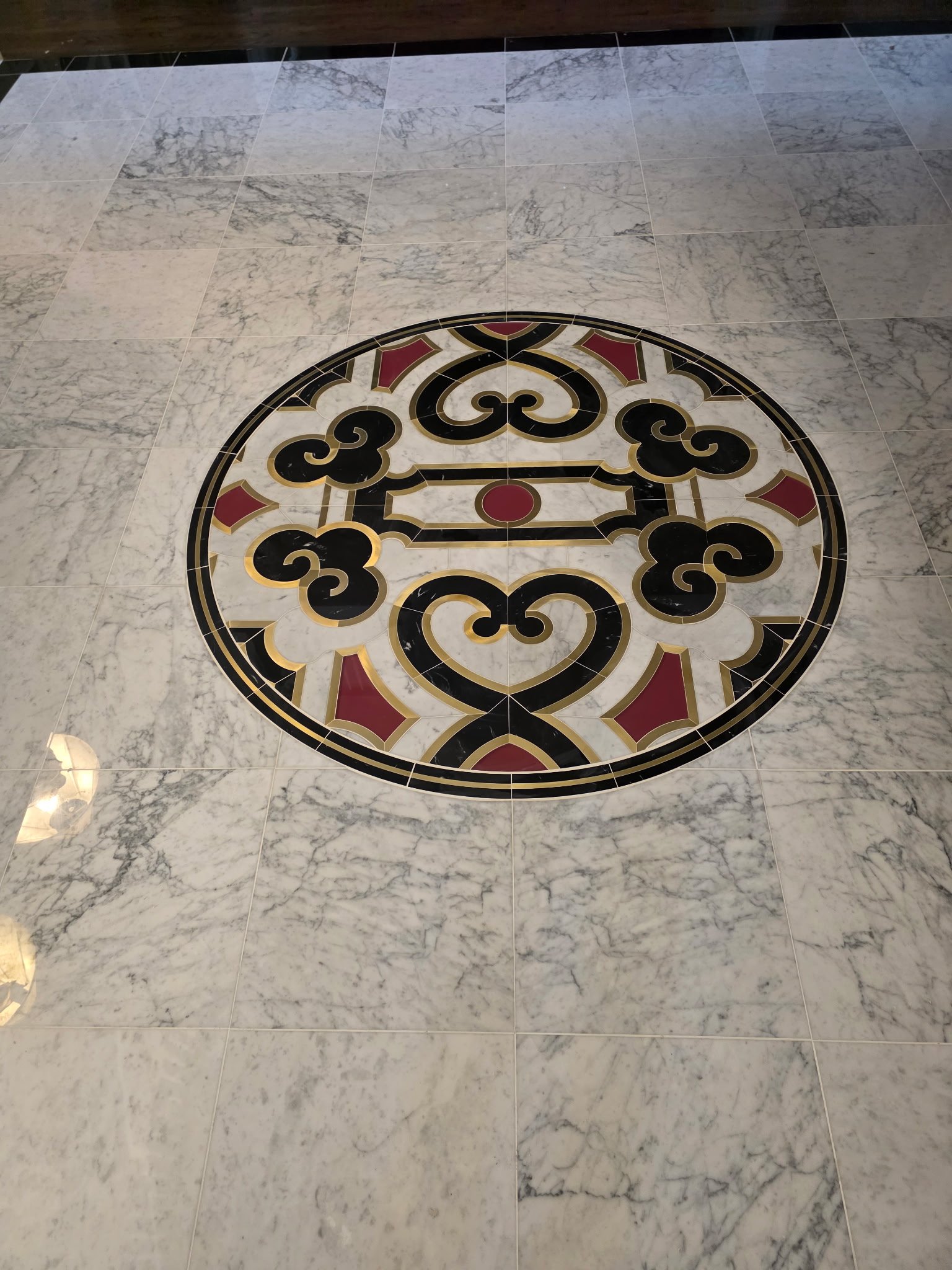 18x18 Carrera Polished Marble with custom Medallion Inlay and black border.