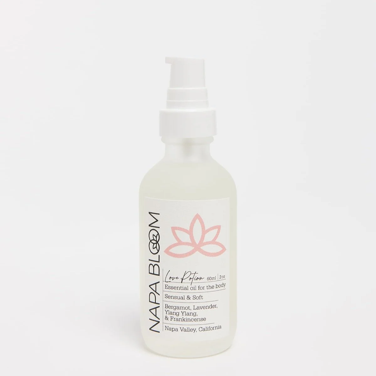 Napa Bloom Love Potion Body Oil — 2 oz frosted white glass travel-size bottle with white label and black text, lotus logo, and white pump top.