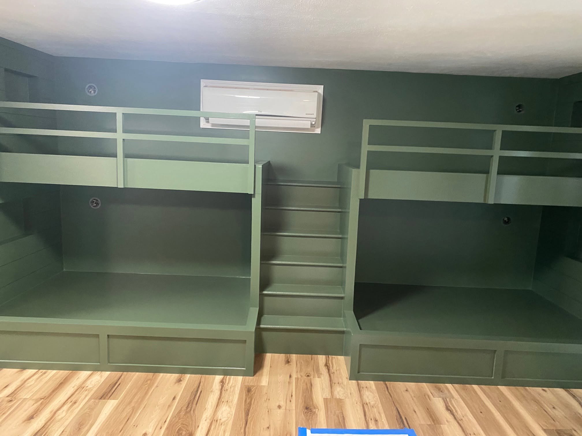 Green built-in bunk beds with central steps in a Goshen room.