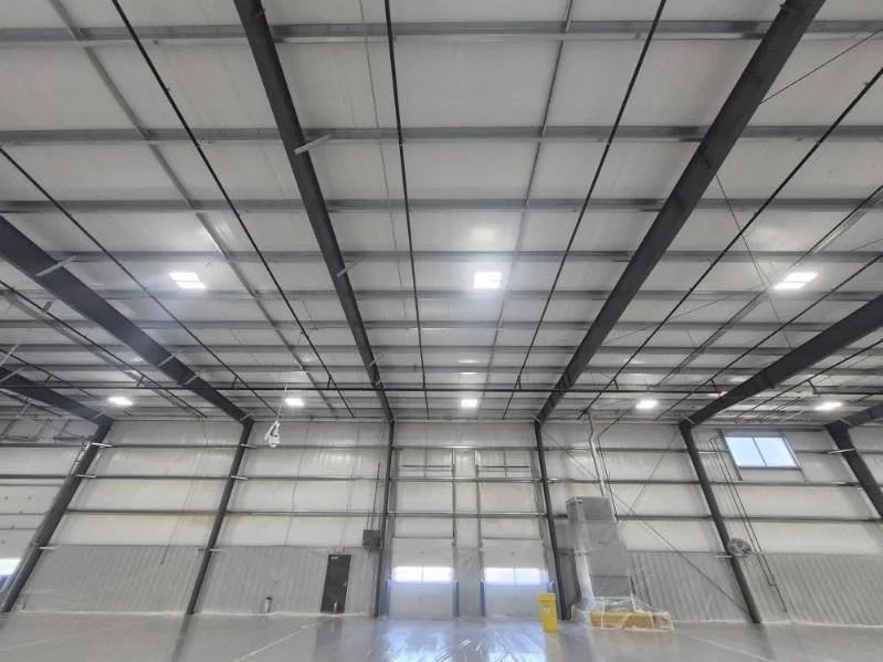 Industrial ceiling beams and wall panels above a large overhead door.