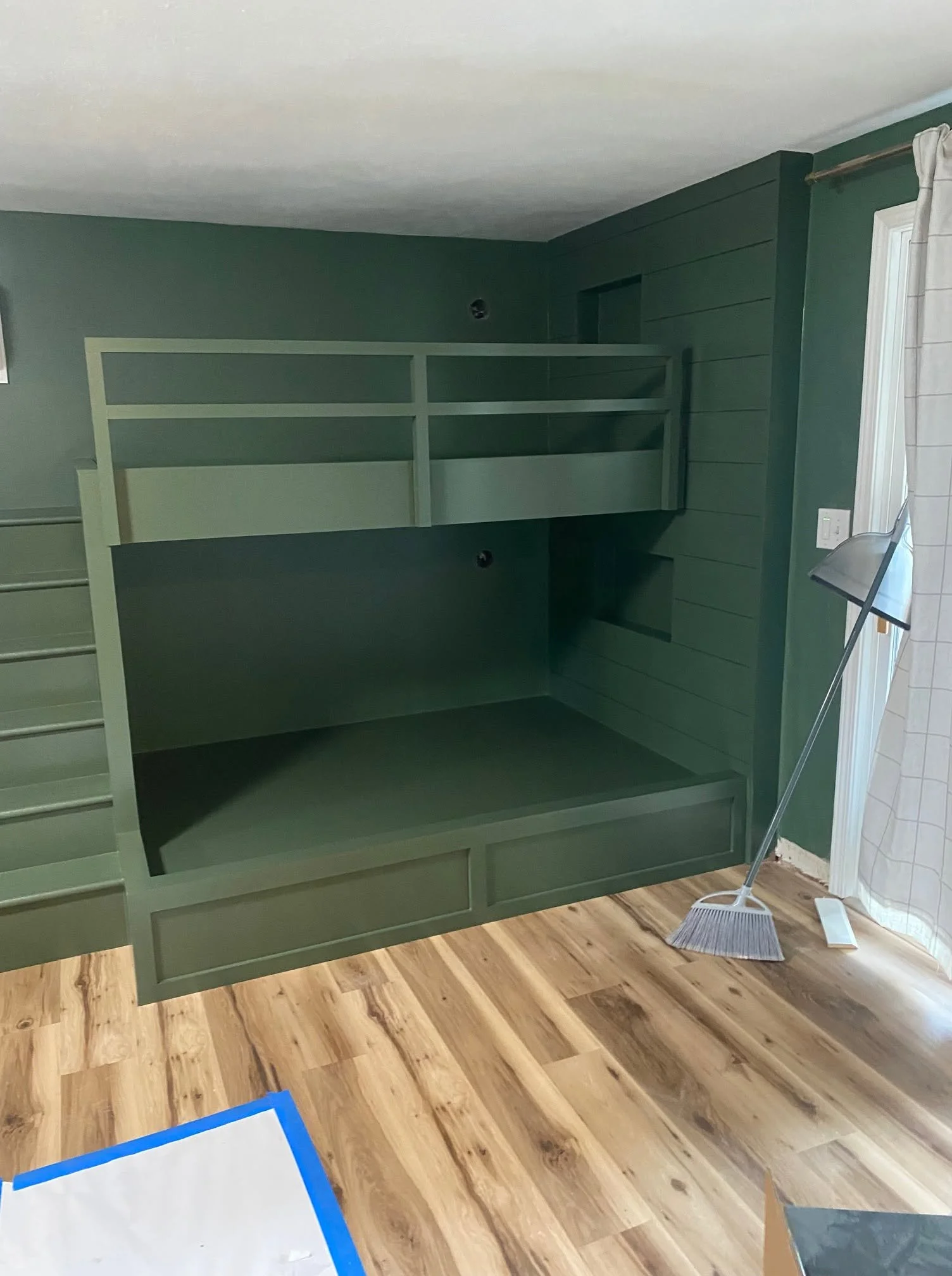 Green built-in bunk bed with matching guardrails and paneled walls.