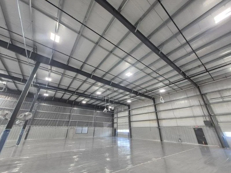 Angled view of an industrial interior with exposed roof framing and an overhead door.