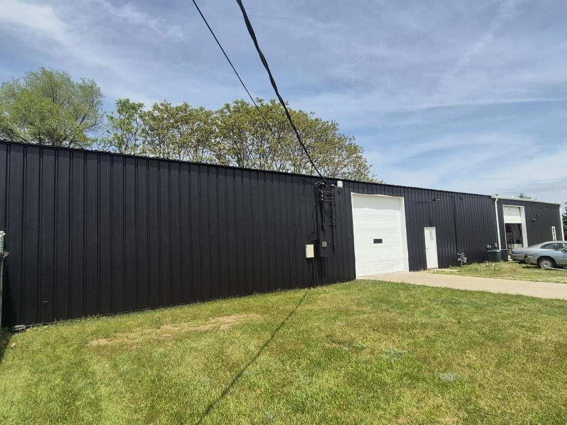 Black-painted side wall of the Pokeden building with a white overhead door.
