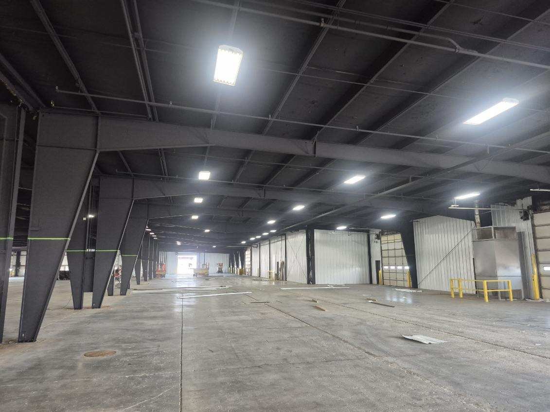 Commercial interior with dark overhead surfaces, exposed beams, and support columns.