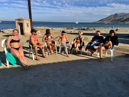 Guests relaxing together in chairs beside the water.