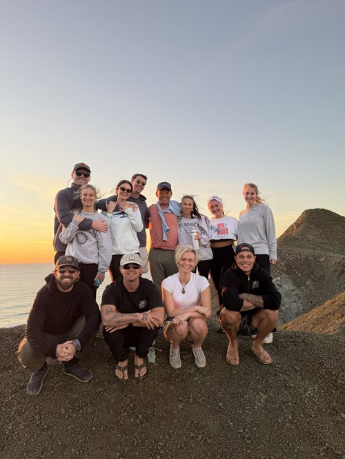 An expedition group gathered outdoors as the sun goes down.