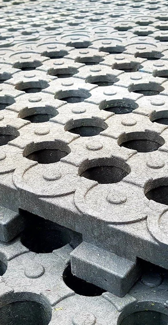 Stacked gray mud grid blocks with circular holes and small raised dots on top, arranged in rows.