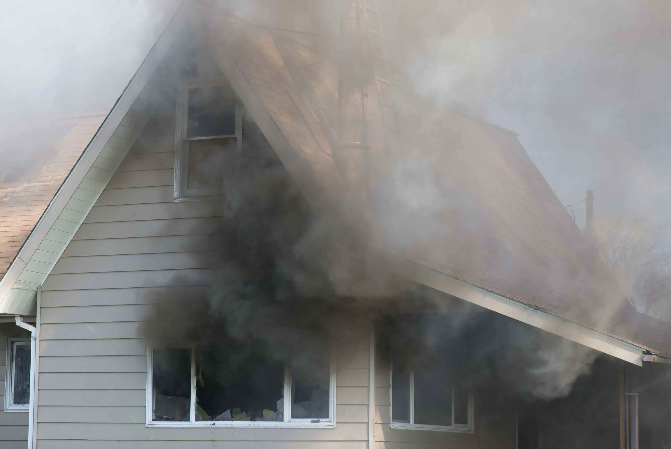 House on fire with thick black smoke coming out of the windows and attic.