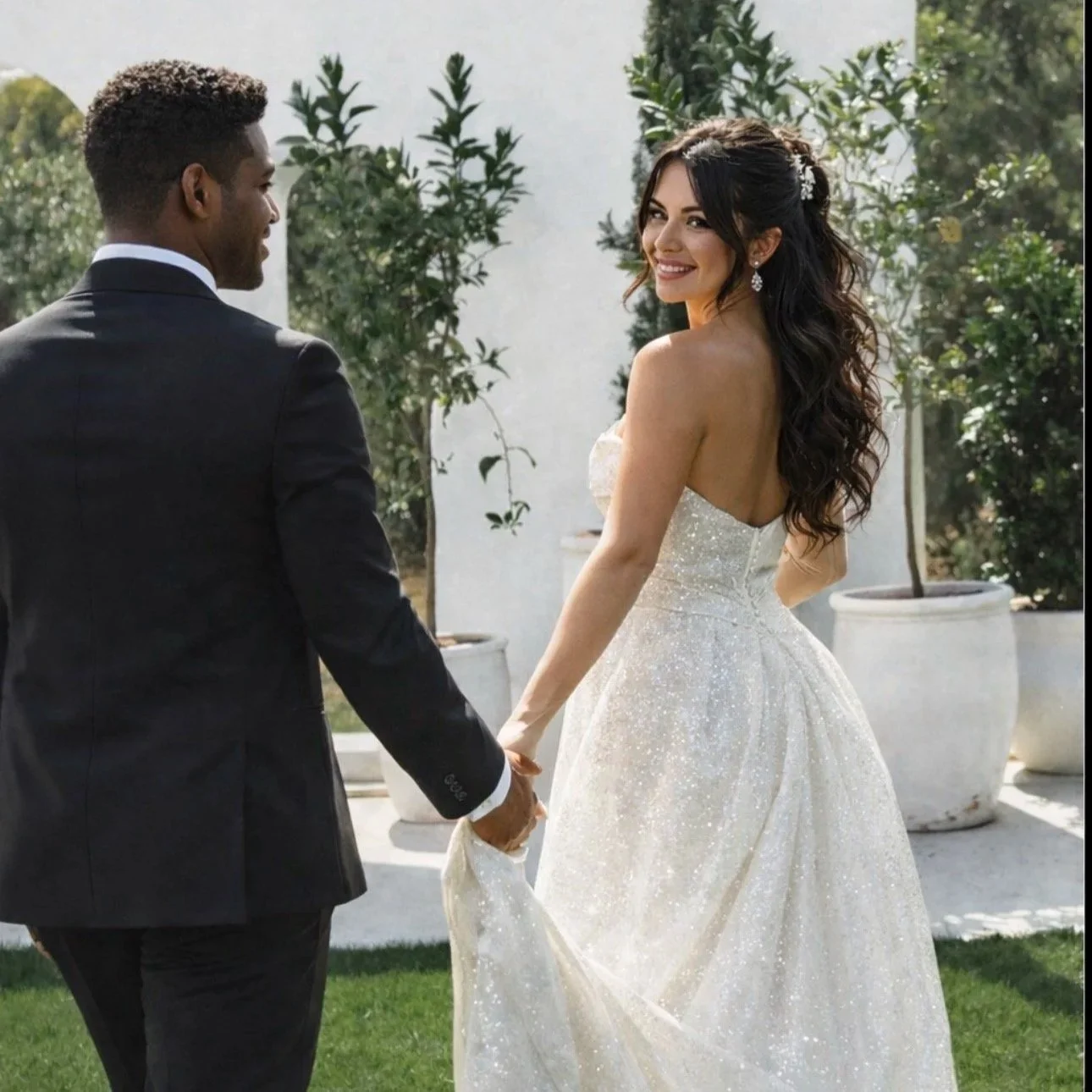 Outdoor wedding ceremony setup with rows of white chairs facing a closed black gate, flanked by trees and greenery, under a string of lights.