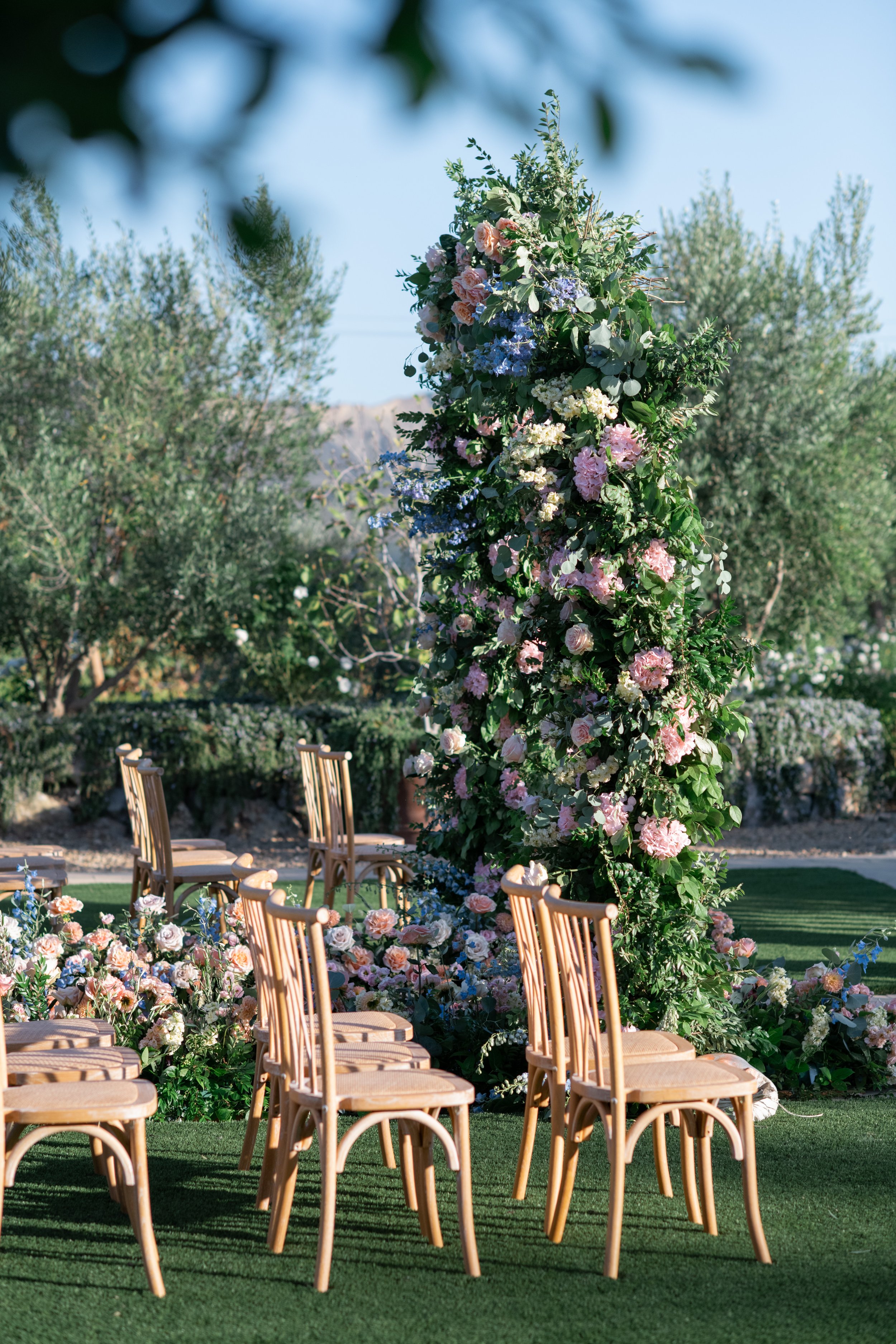 Outdoor wedding ceremony setup with floral arch and chairs on a grassy area