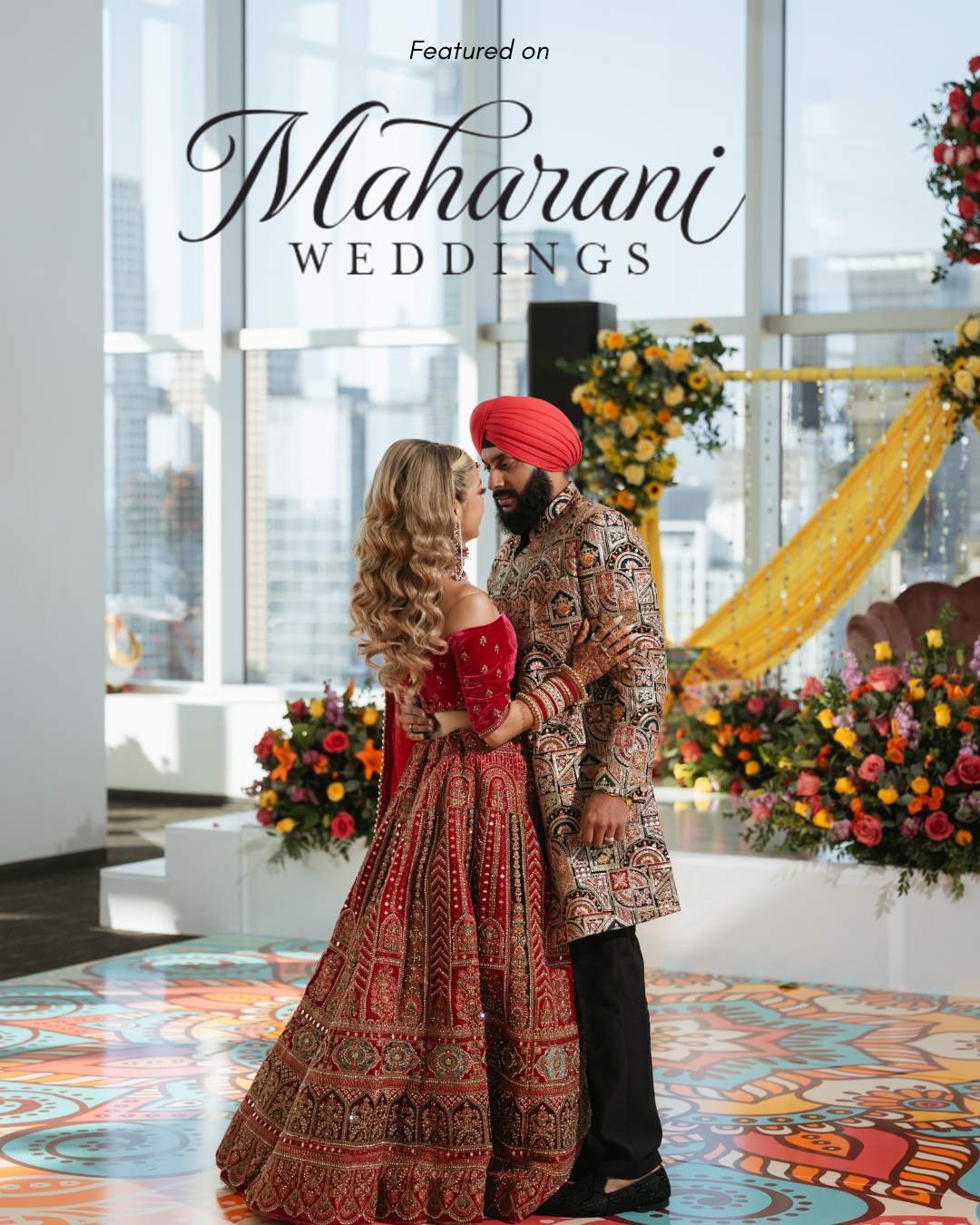 A couple dressed in traditional Indian wedding attire sharing a dance in front of a decorated arch with flowers, in a bright room with city views, with the text 'Featured on Maharani Weddings' above them.