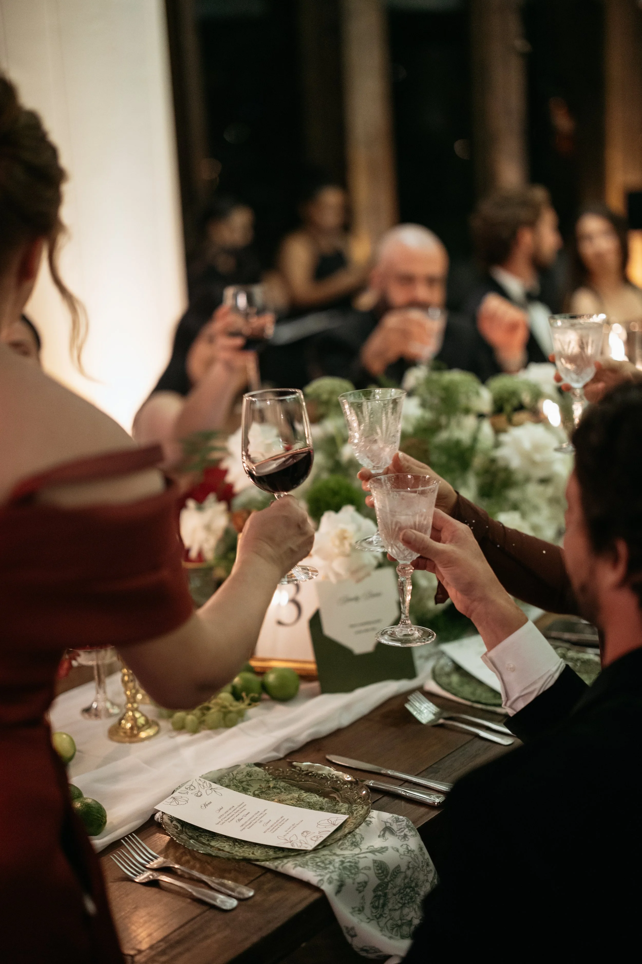 Guests at a formal dinner raising glasses for a toast at a decorated table festively set for a celebration or special occasion.