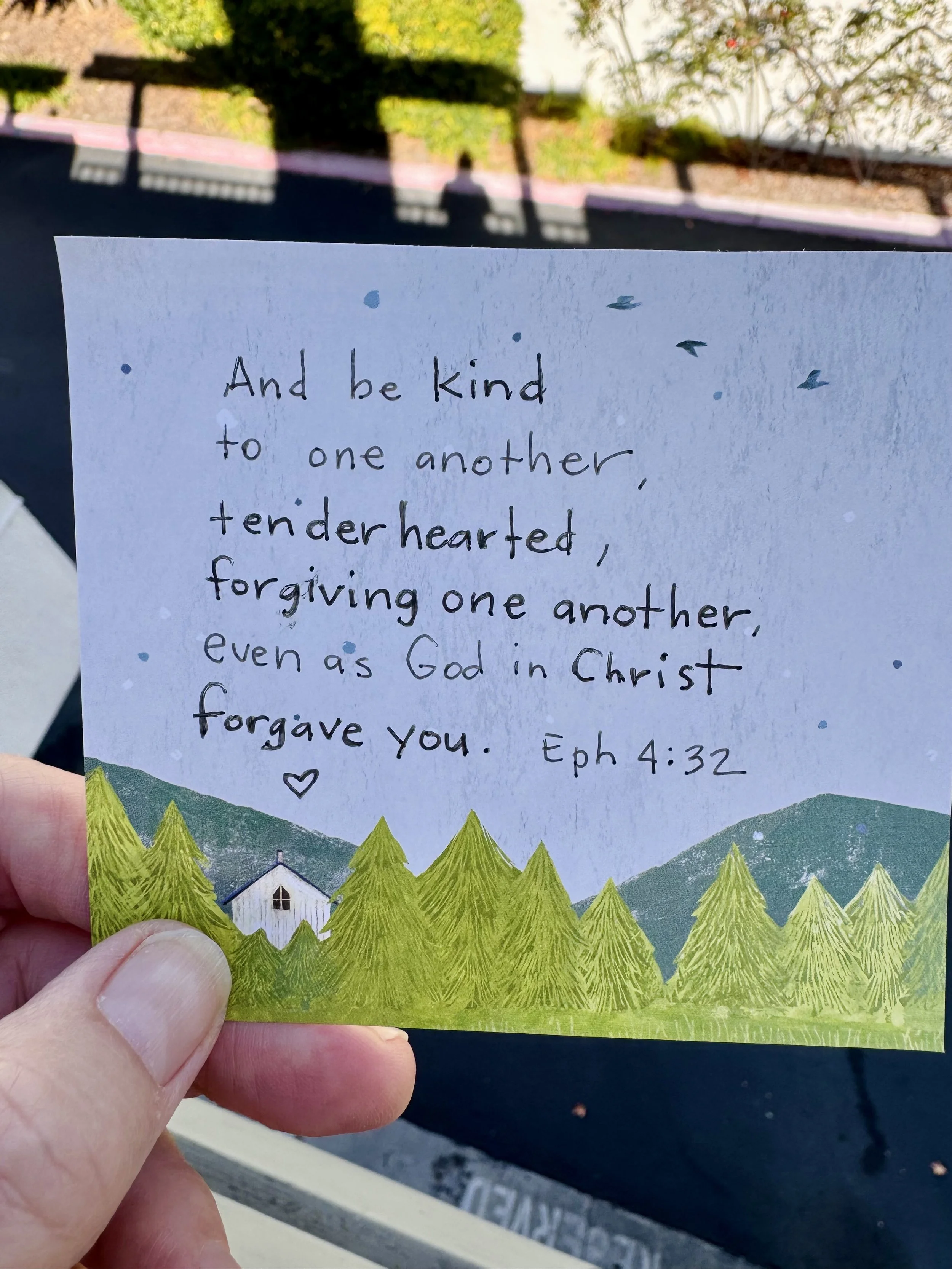 Ephesians 4:32 handwritten on a notecard with trees, mountains, and a house