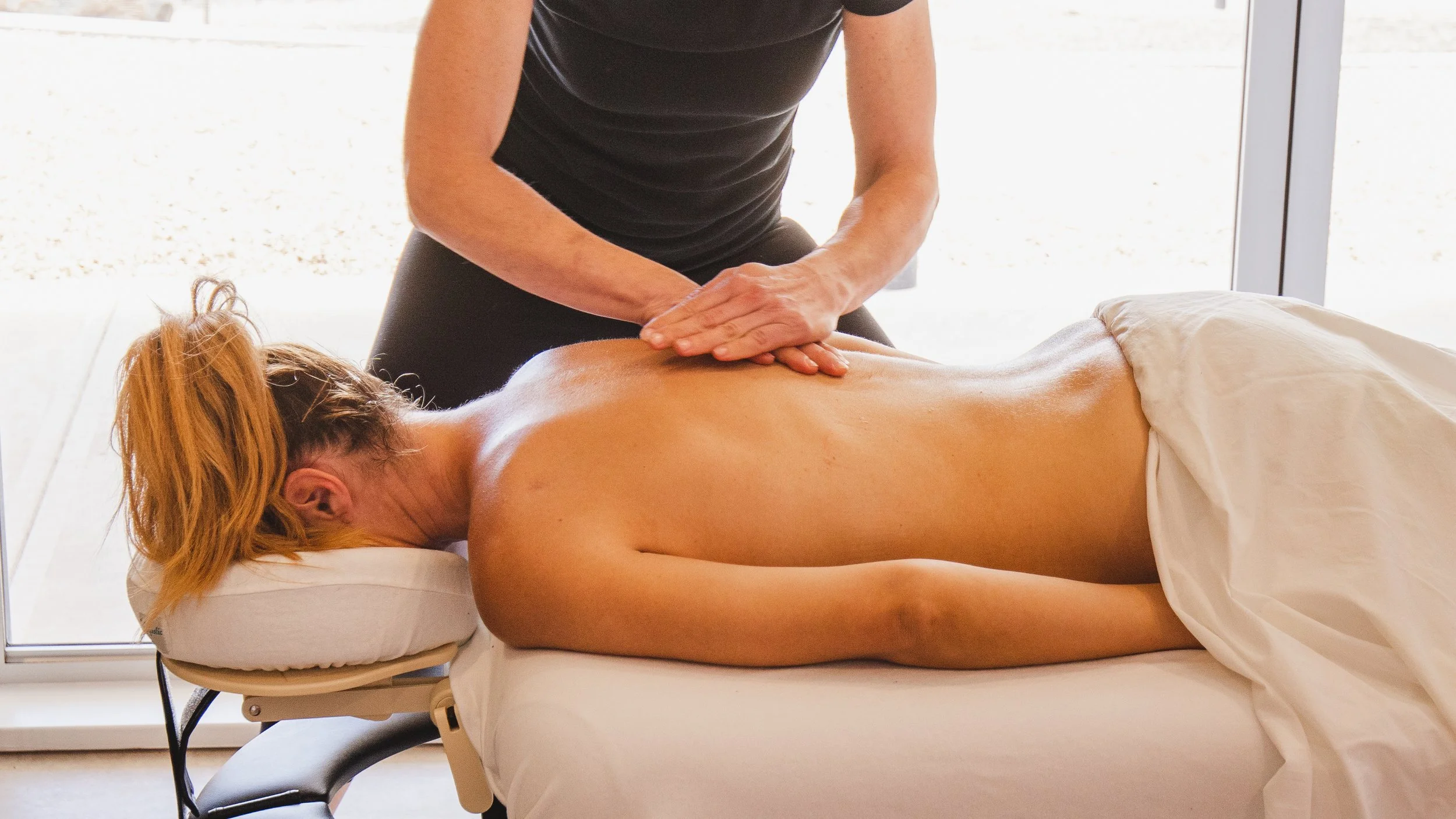 A person receiving a back massage from a therapist in a clinical setting.