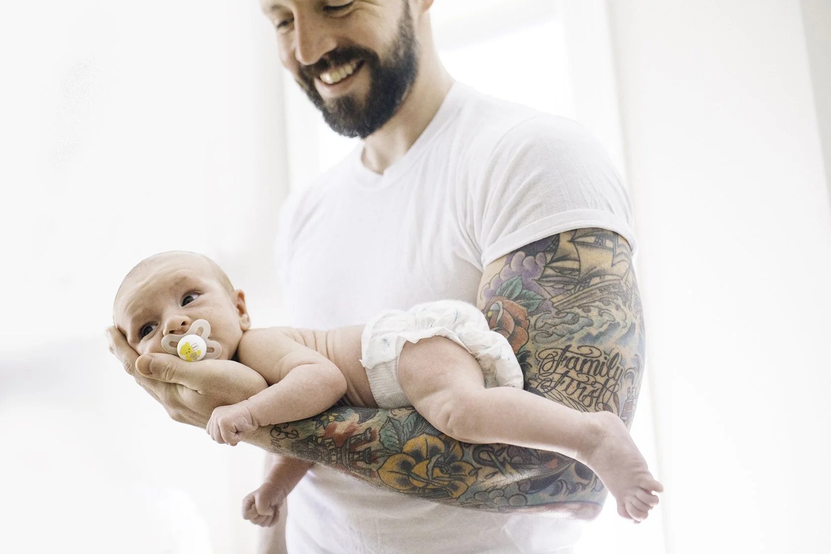 A new father holds his newborn baby in a professional newborn session photo by zenobia studios Jennifer Lamy.