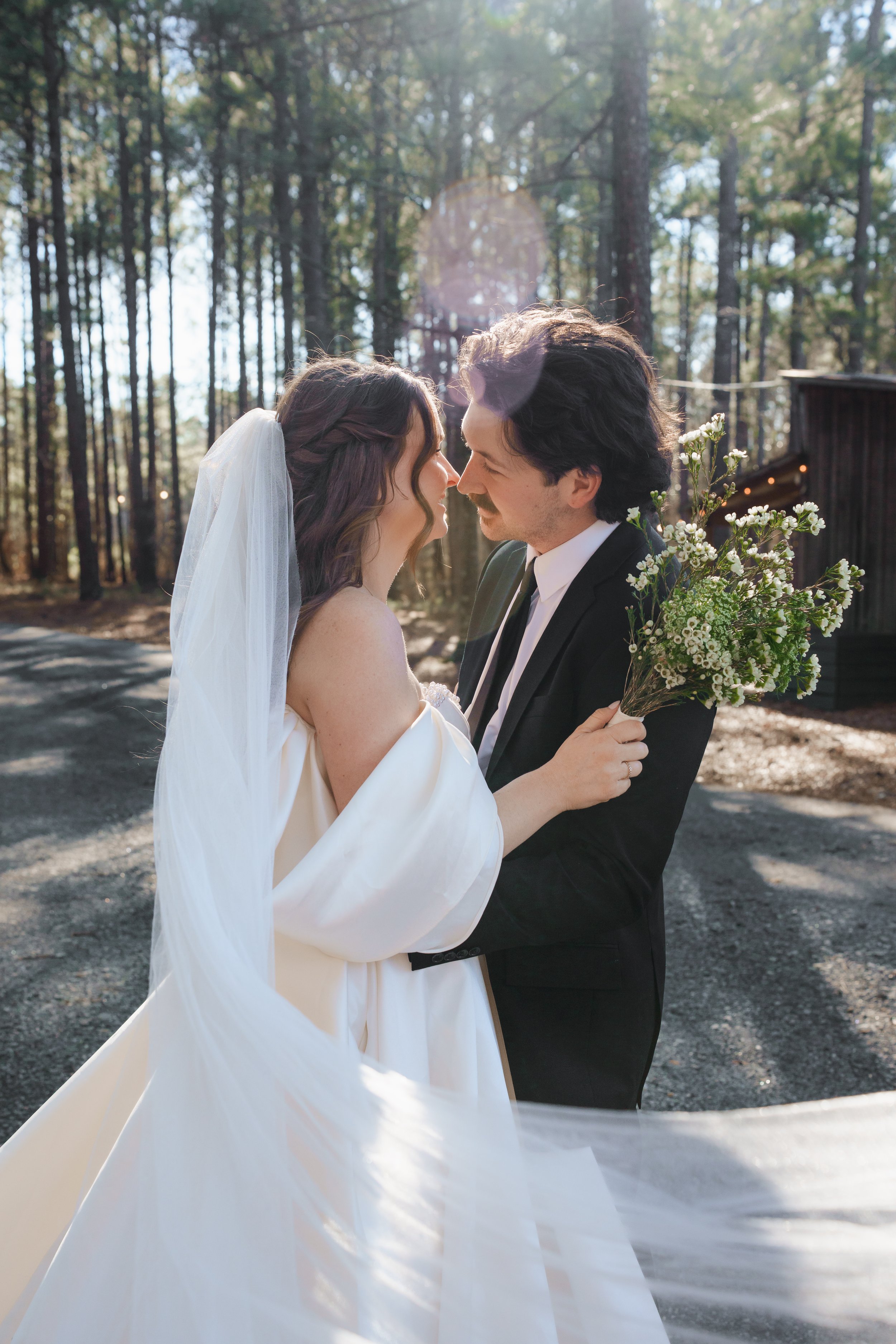 Bride and Groom almost kissing with sunlight filtering through the trees