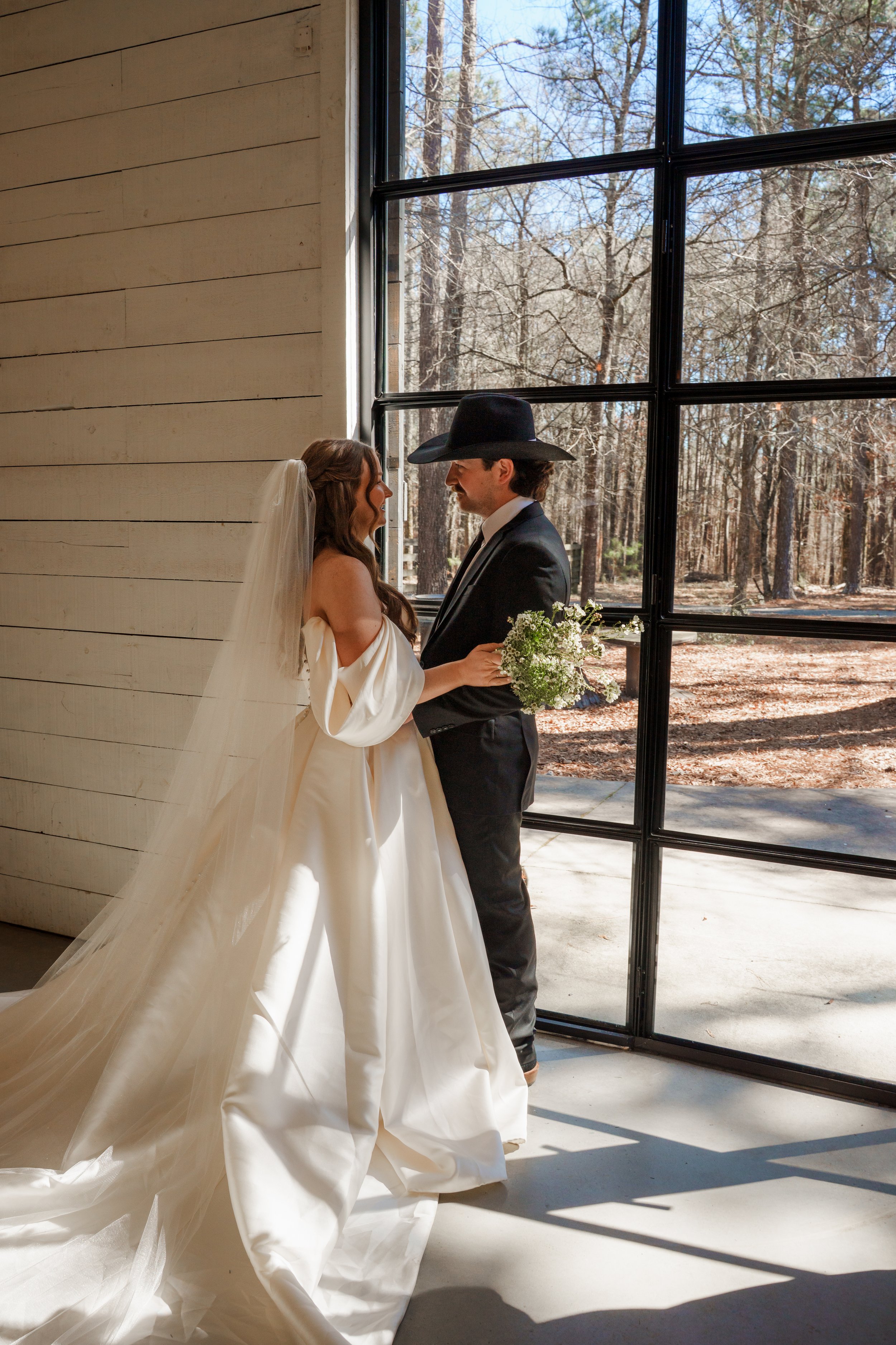 Bride and Groom having a first look by the window of their reception space