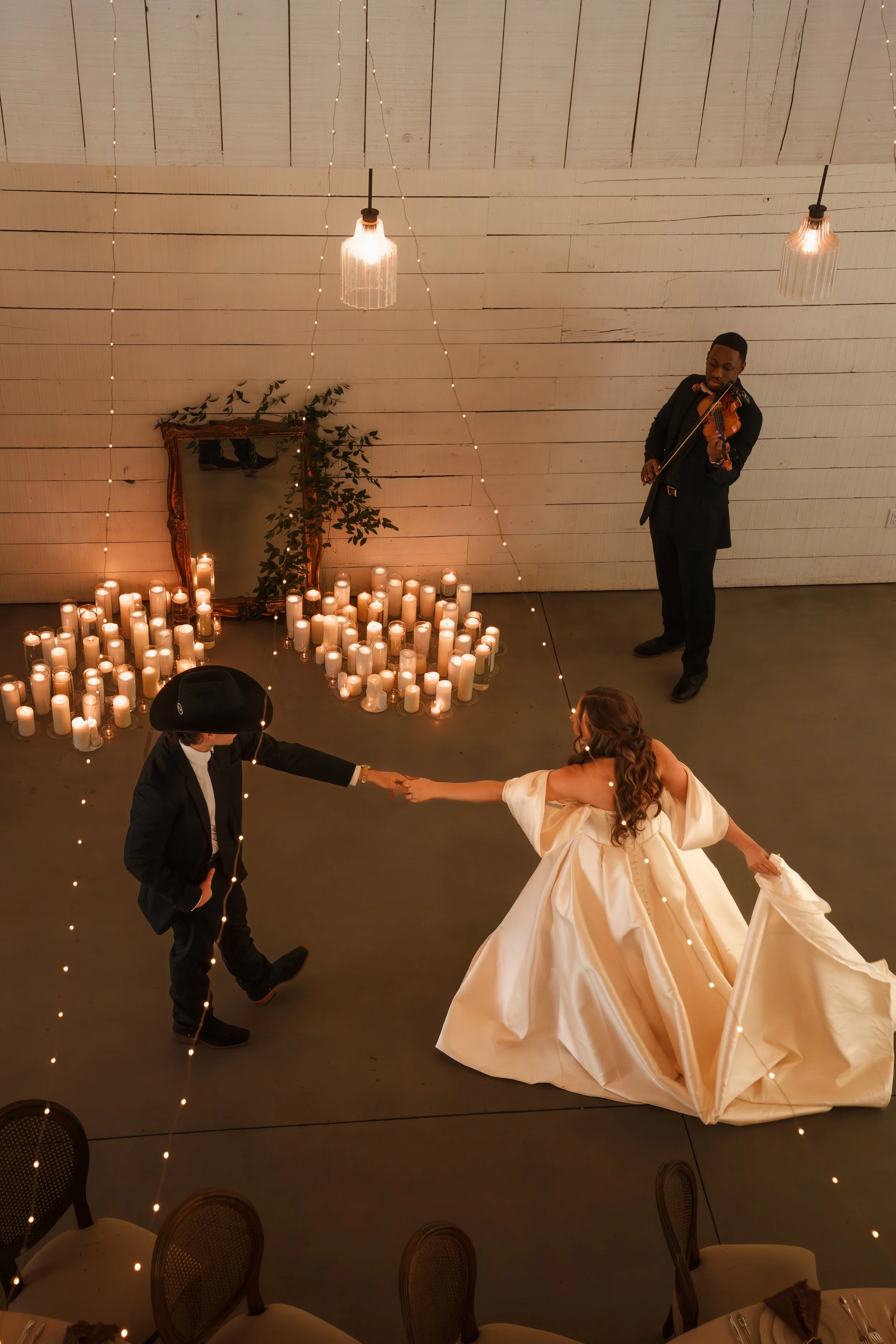 Bride and Groom dancing in their candlelit reception space with a violinist playing their song
