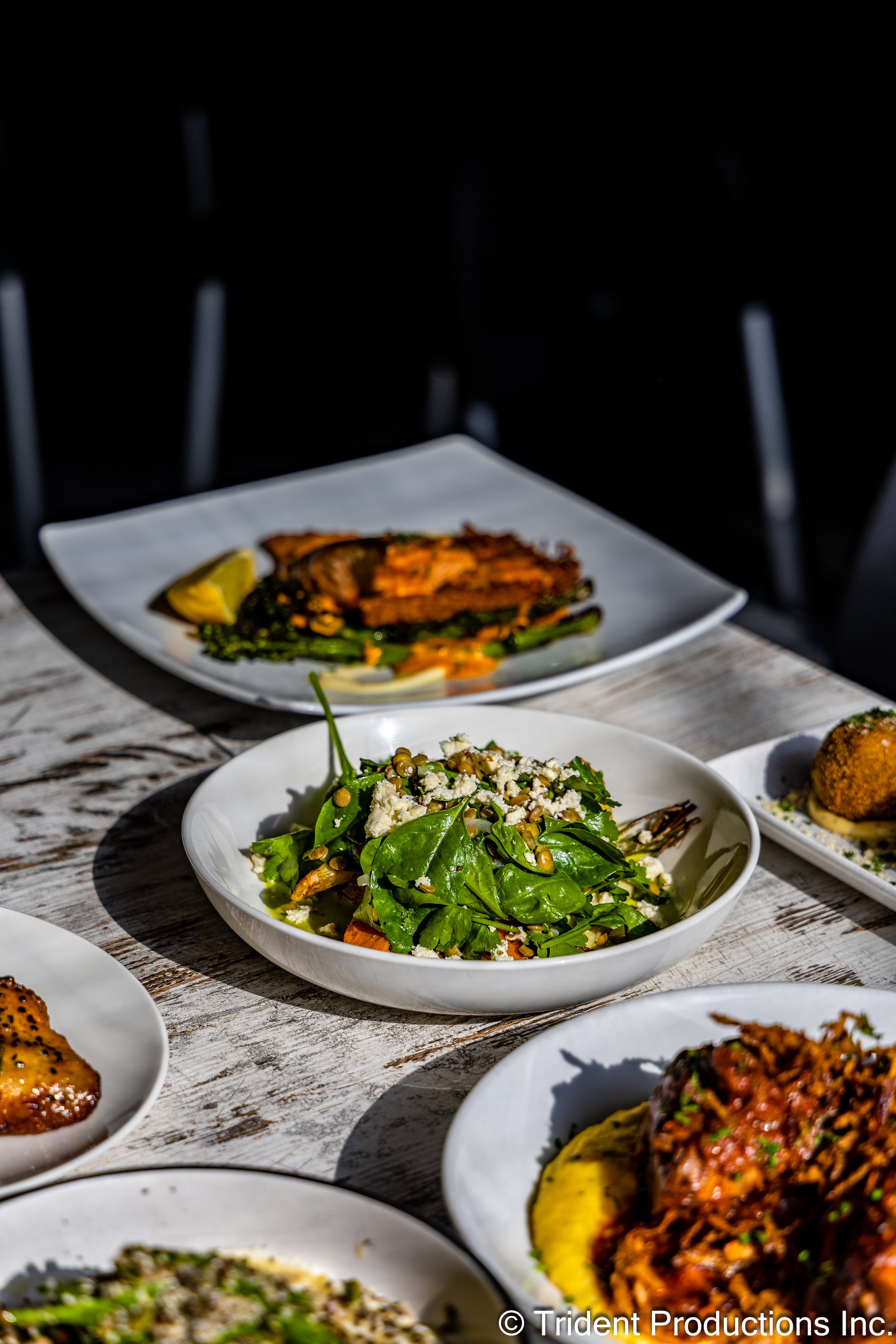 Assorted dishes of salads and main courses on a rustic wooden table.