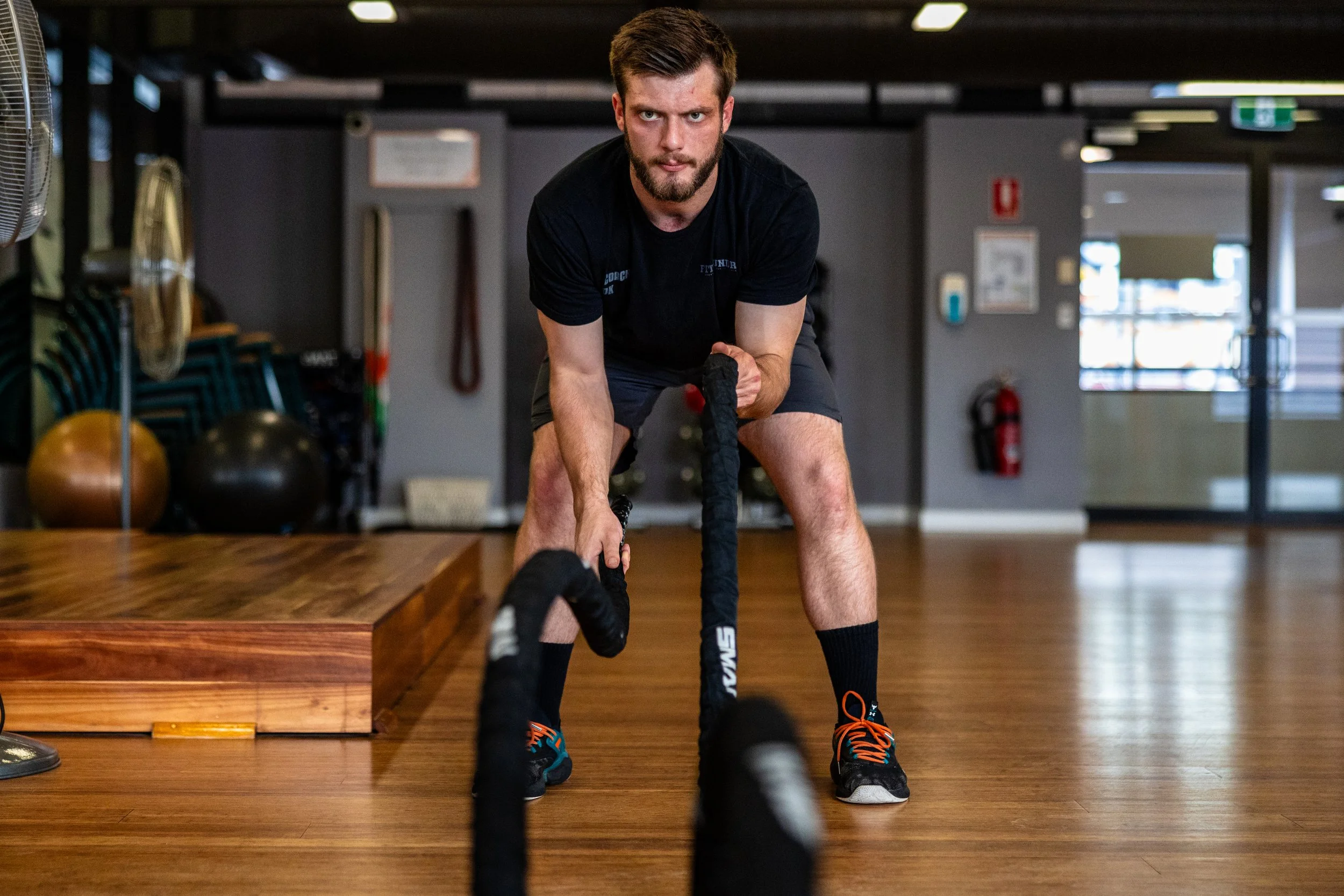 Man performing battle ropes exercise in gym.