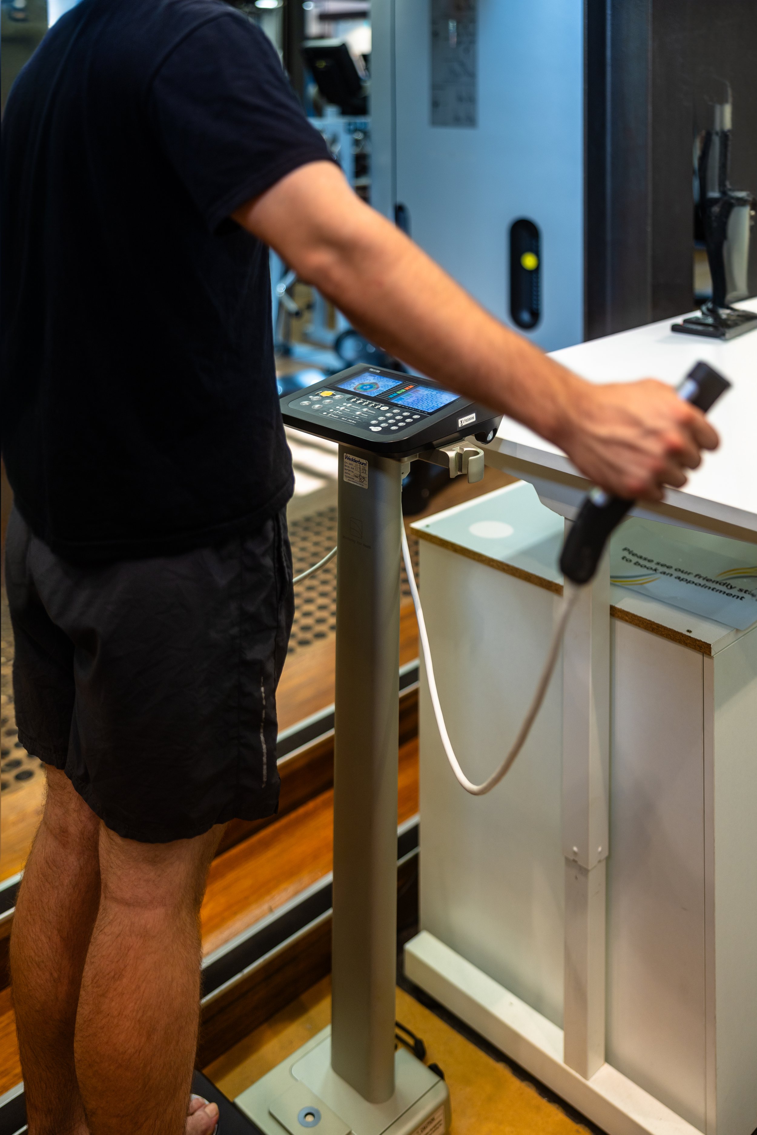 Person standing at a checkout counter in a store, using a handheld device connected to a payment terminal.