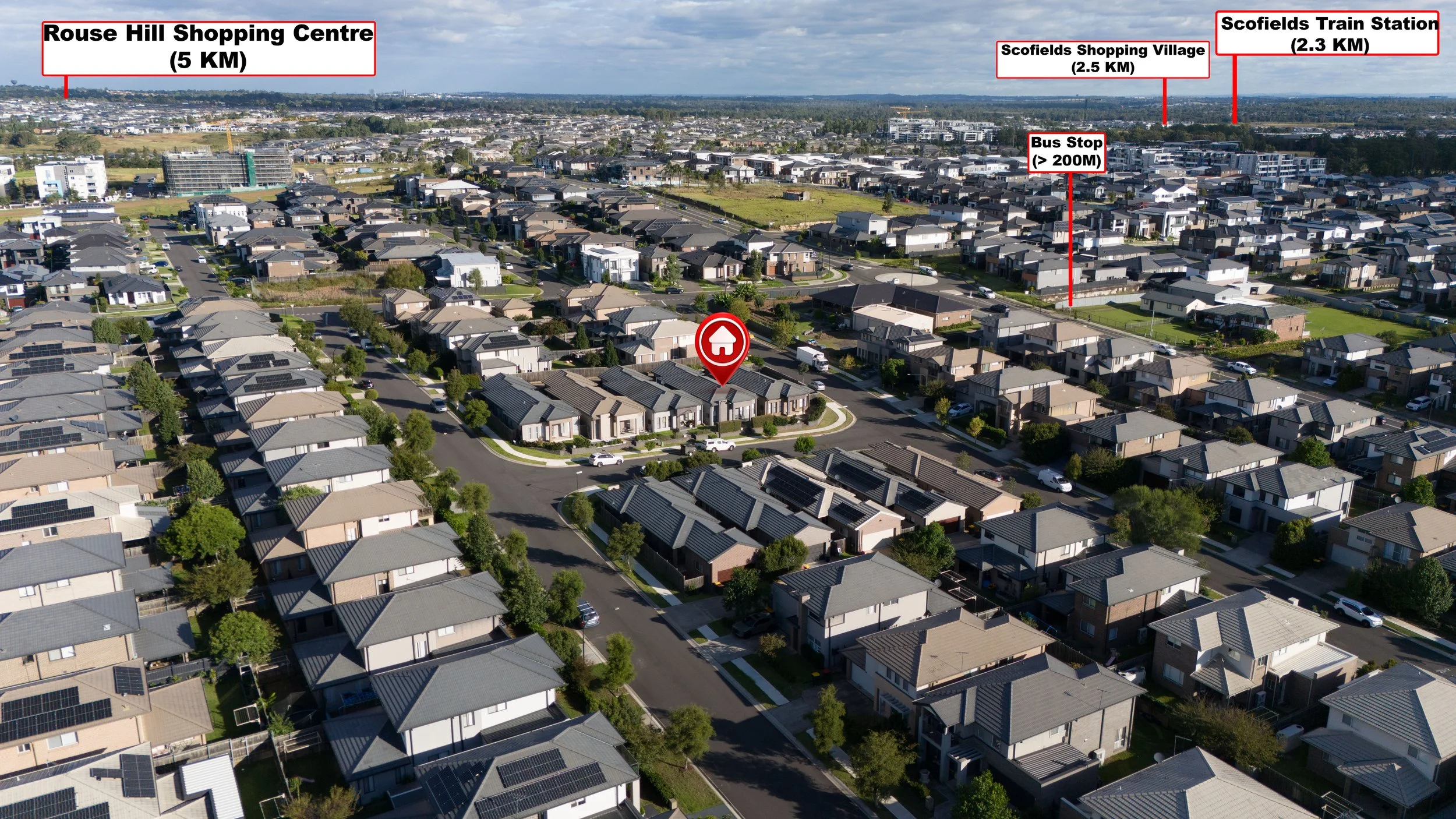 An aerial view of a residential neighborhood with numerous houses, roads, and trees. In the background, there are labels indicating distances to various locations: Rouse Hill Shopping Centre (5 km), Scofields Shopping Village (2.5 km), Scofields Trai