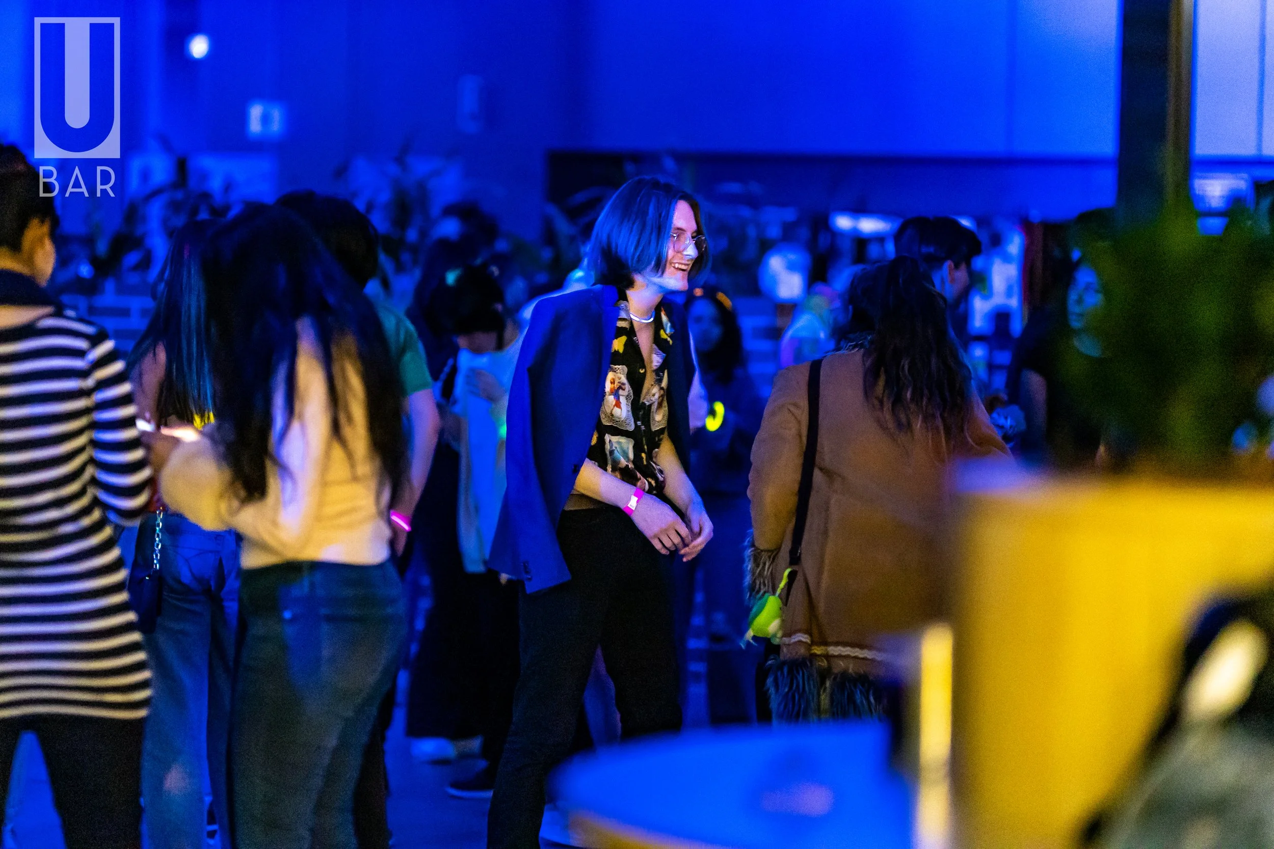 People dancing and socializing at a lively bar with blue lighting