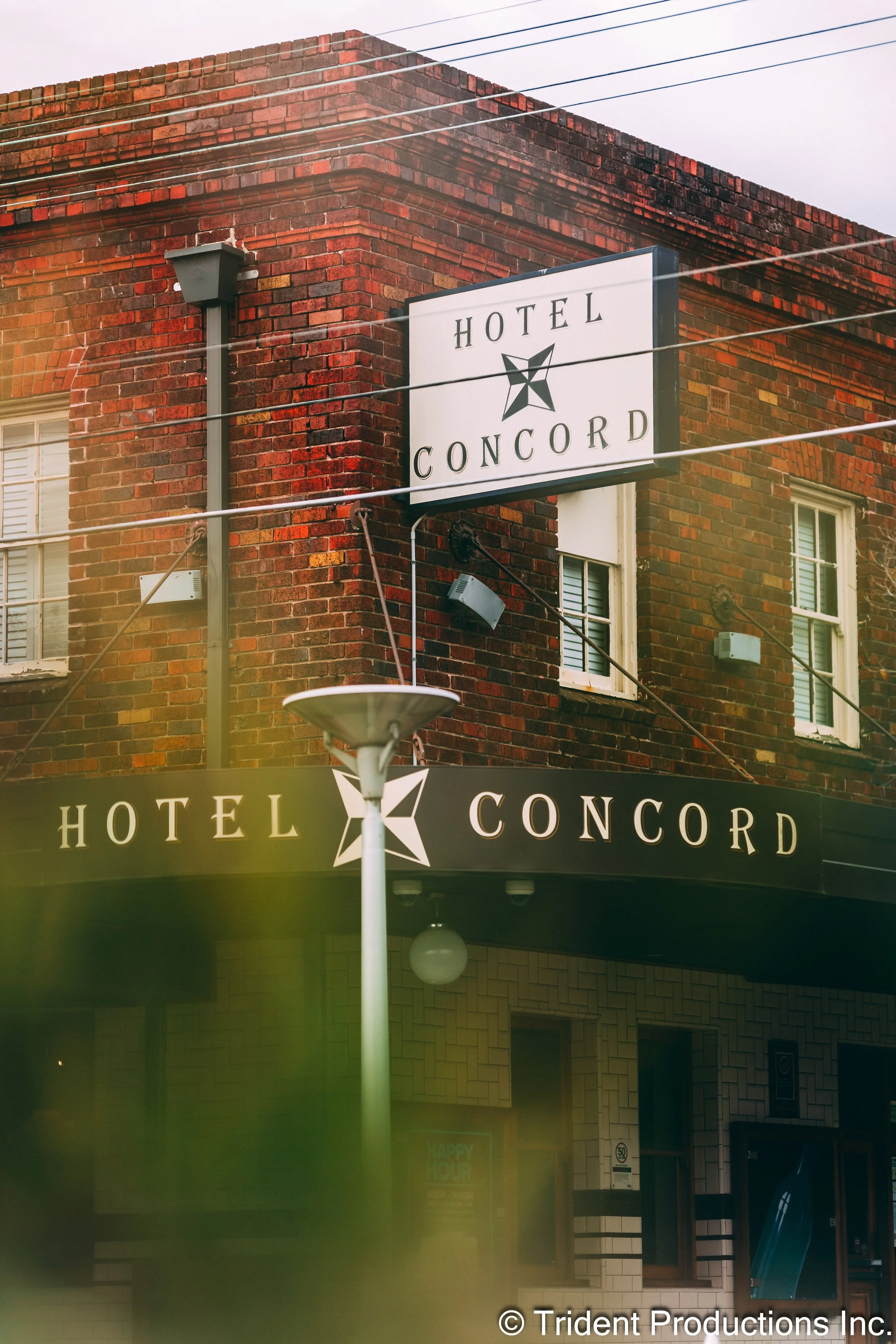 Sign for Hotel Concord on a brick building, featuring a black and white sign with a star logo and the hotel name.
