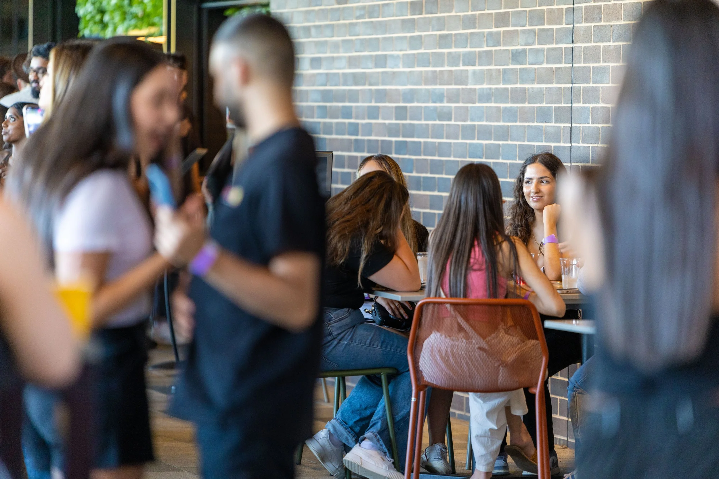 People socializing in a cafe with a brick wall background and casual attire.