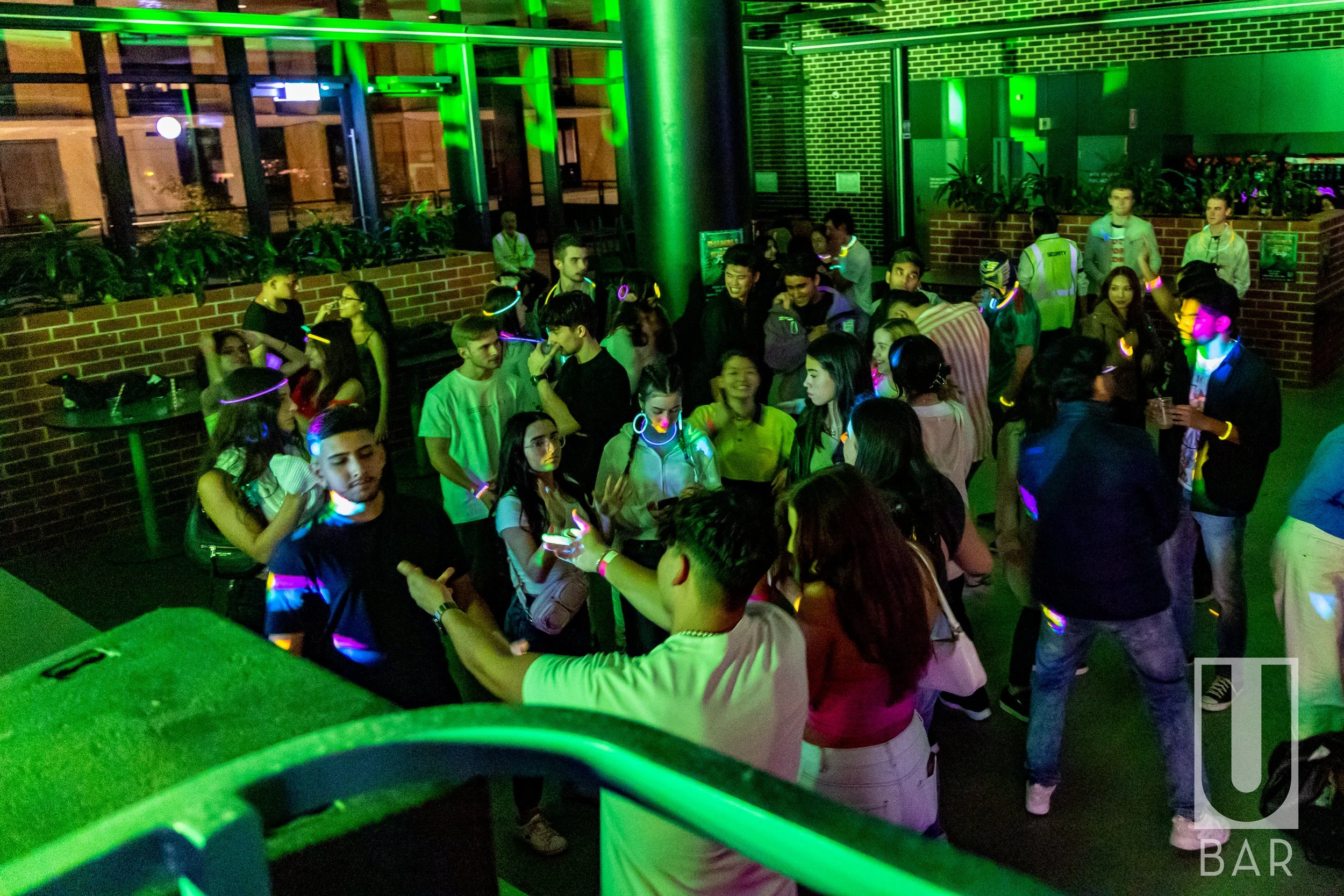 Crowd of young people at a nightclub dance party with neon lights.