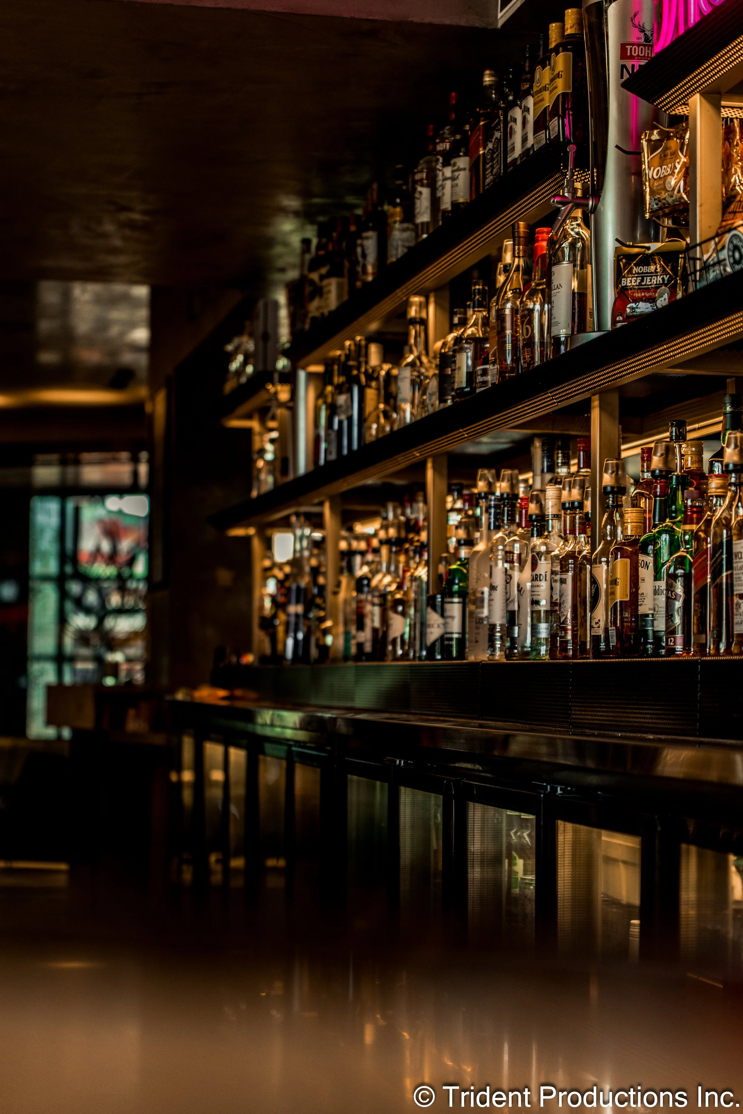 A bar shelf filled with various bottles of liquor in dim lighting.