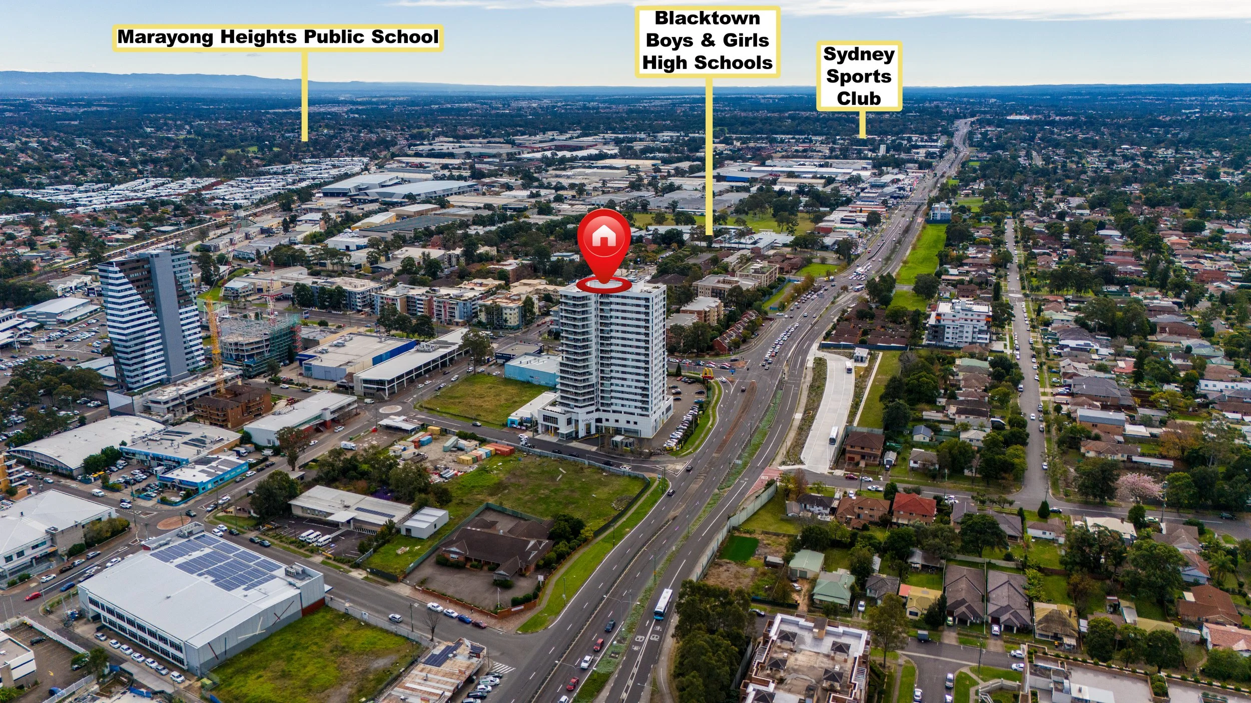 Aerial view of a cityscape with a tall white building marked with a red pin and home icon. In the background, there are labels pointing to Marayong Heights Public School, Blacktown Boys & Girls High Schools, and Sydney Sports Club. The city features 