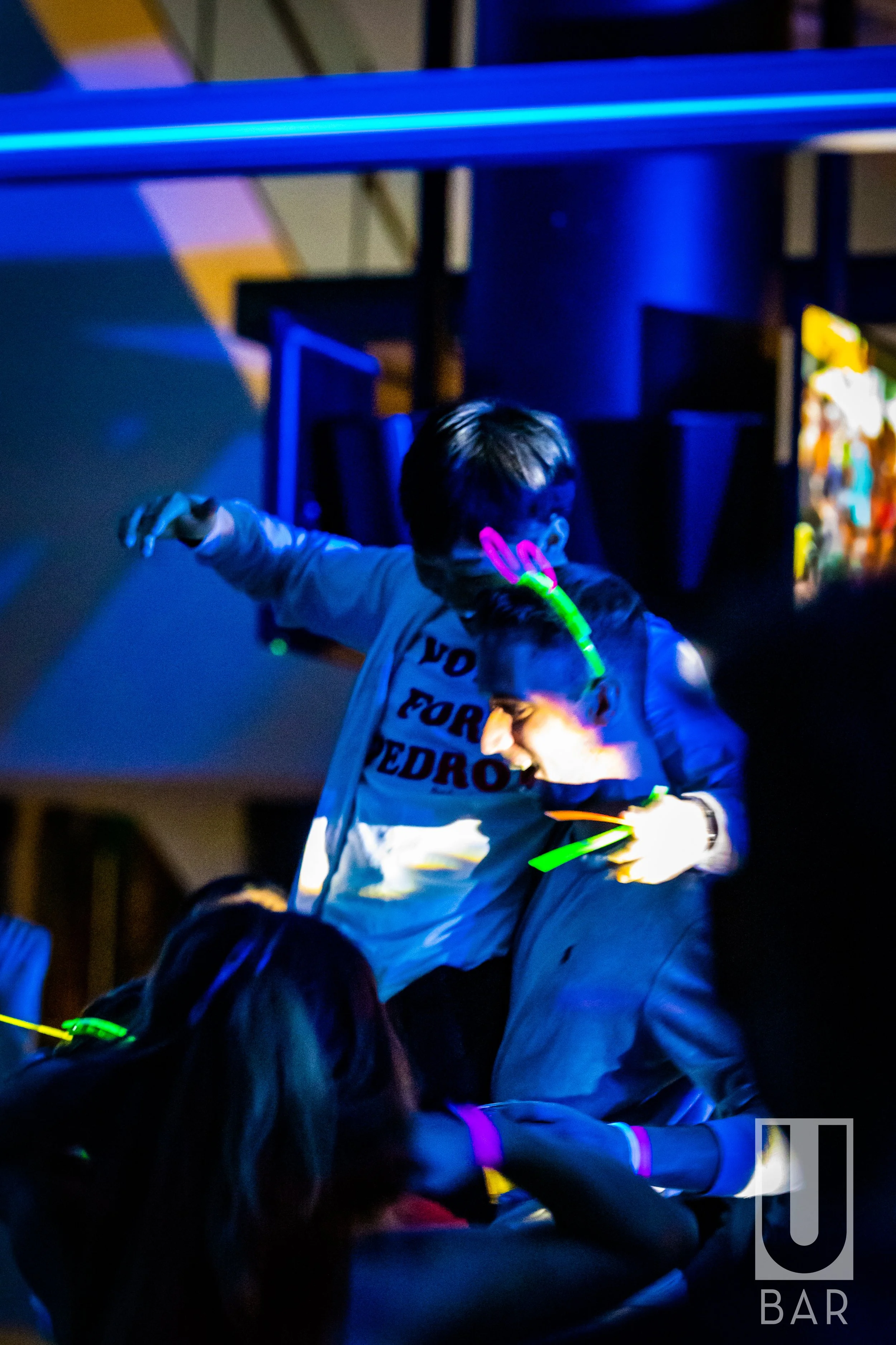 Children at a glow-in-the-dark party wearing neon accessories and enjoying the event in a dark room.