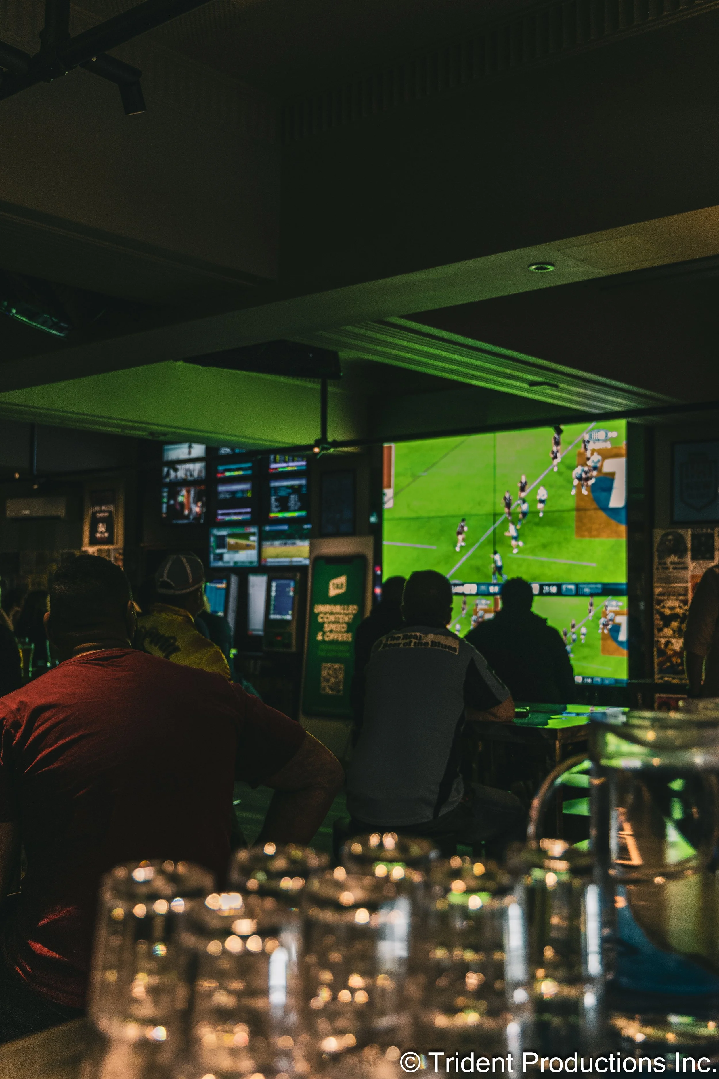People watching a football game on multiple screens in a sports bar.