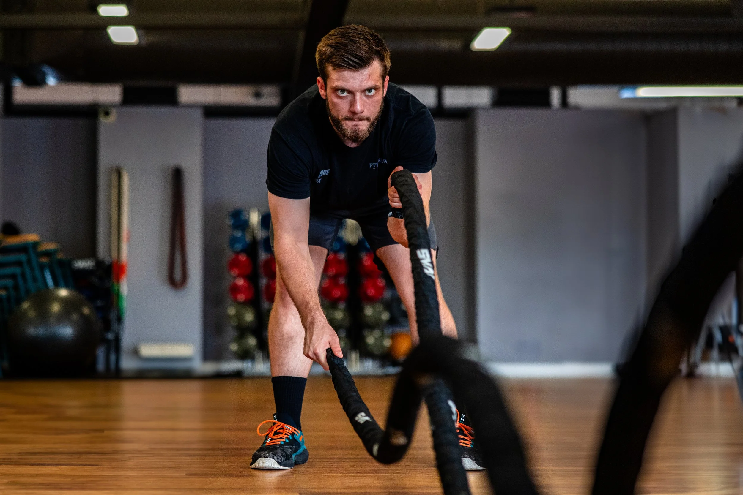 Man exercising with battle ropes in a gym.