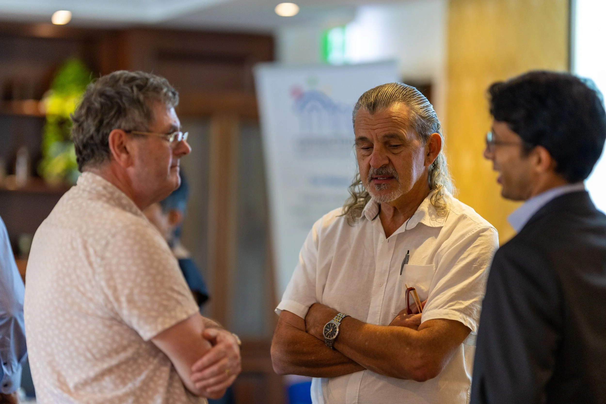 Three men engaged in conversation at a professional event or meeting.