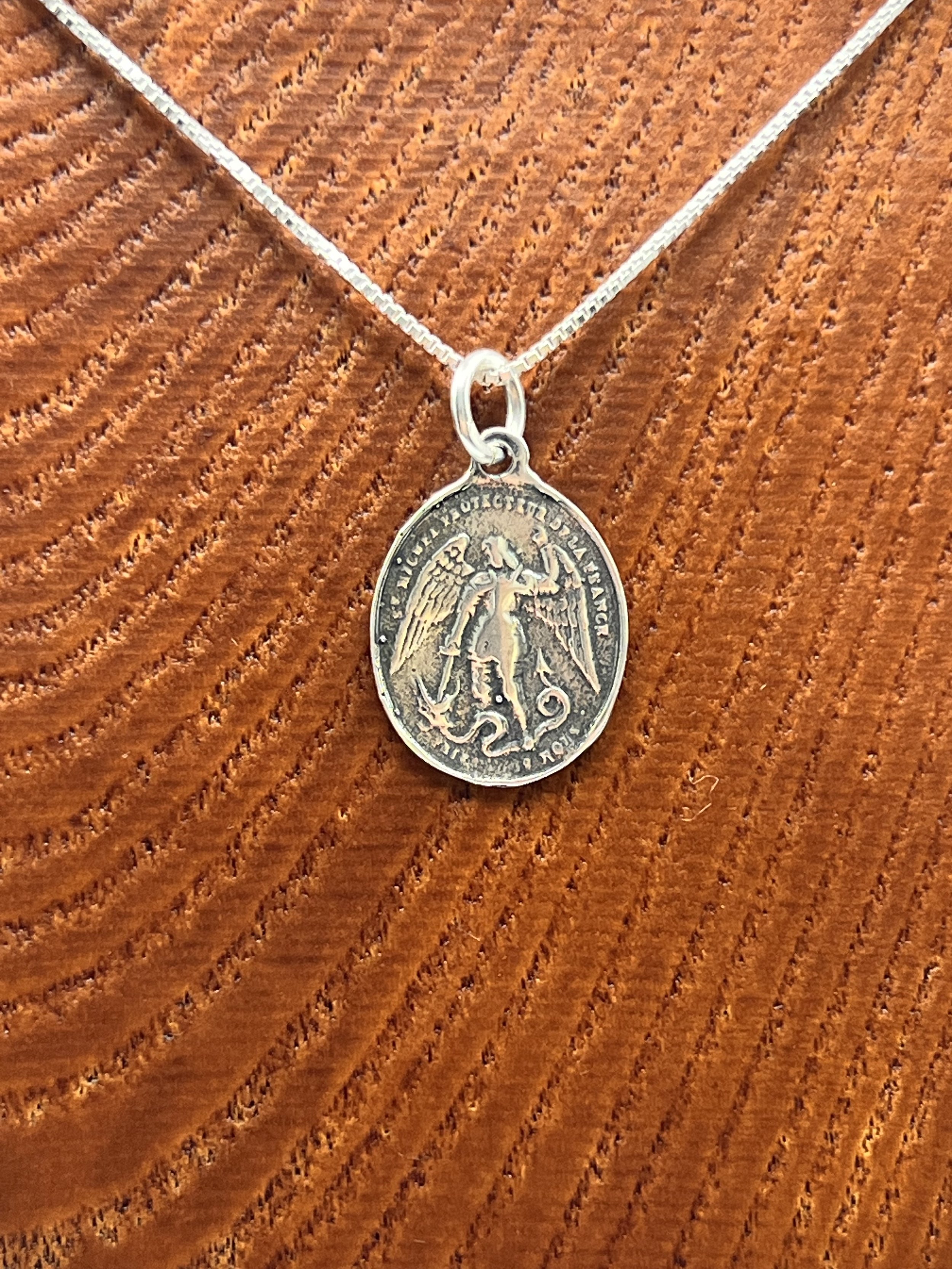 Archangel Michael Frequency Jewelry Pendant displayed on wooden form closeup.