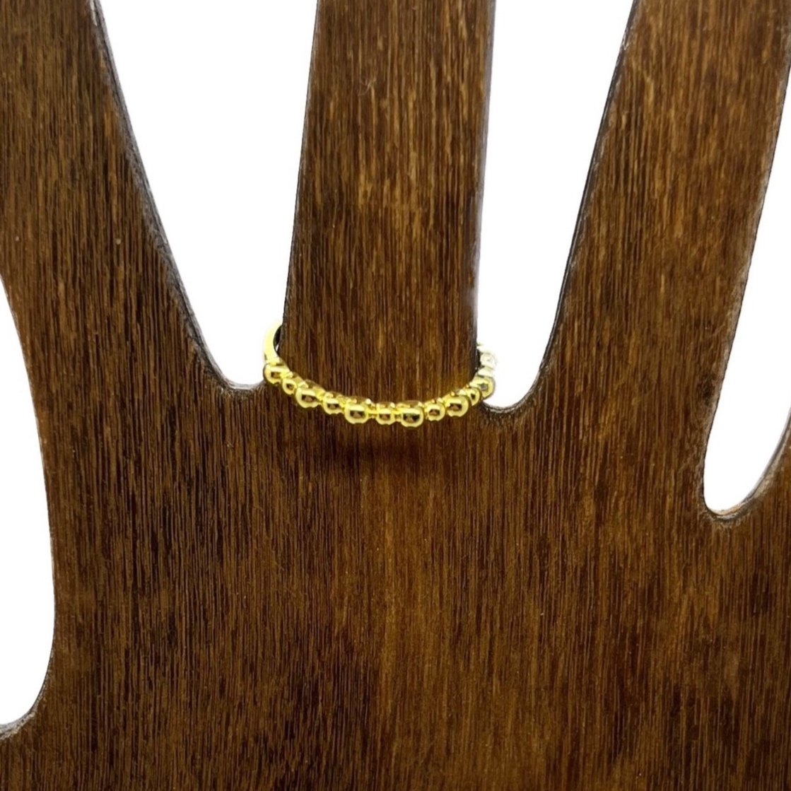 A 14k gold ring on hand model, featuring a delicate row of polished golden beads along the front. Infused with 7.83 Hz frequency.