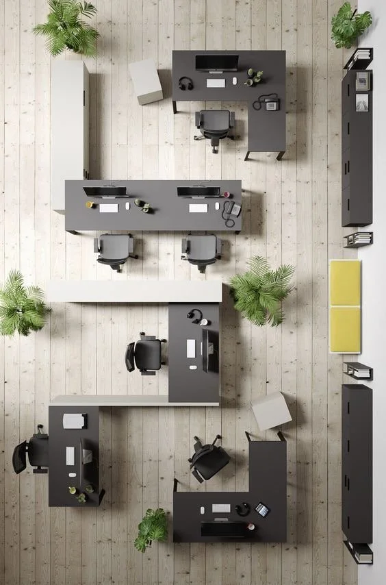 Top-down view of an office with four desks, multiple chairs, plants, lockers, and office supplies on light wooden flooring.