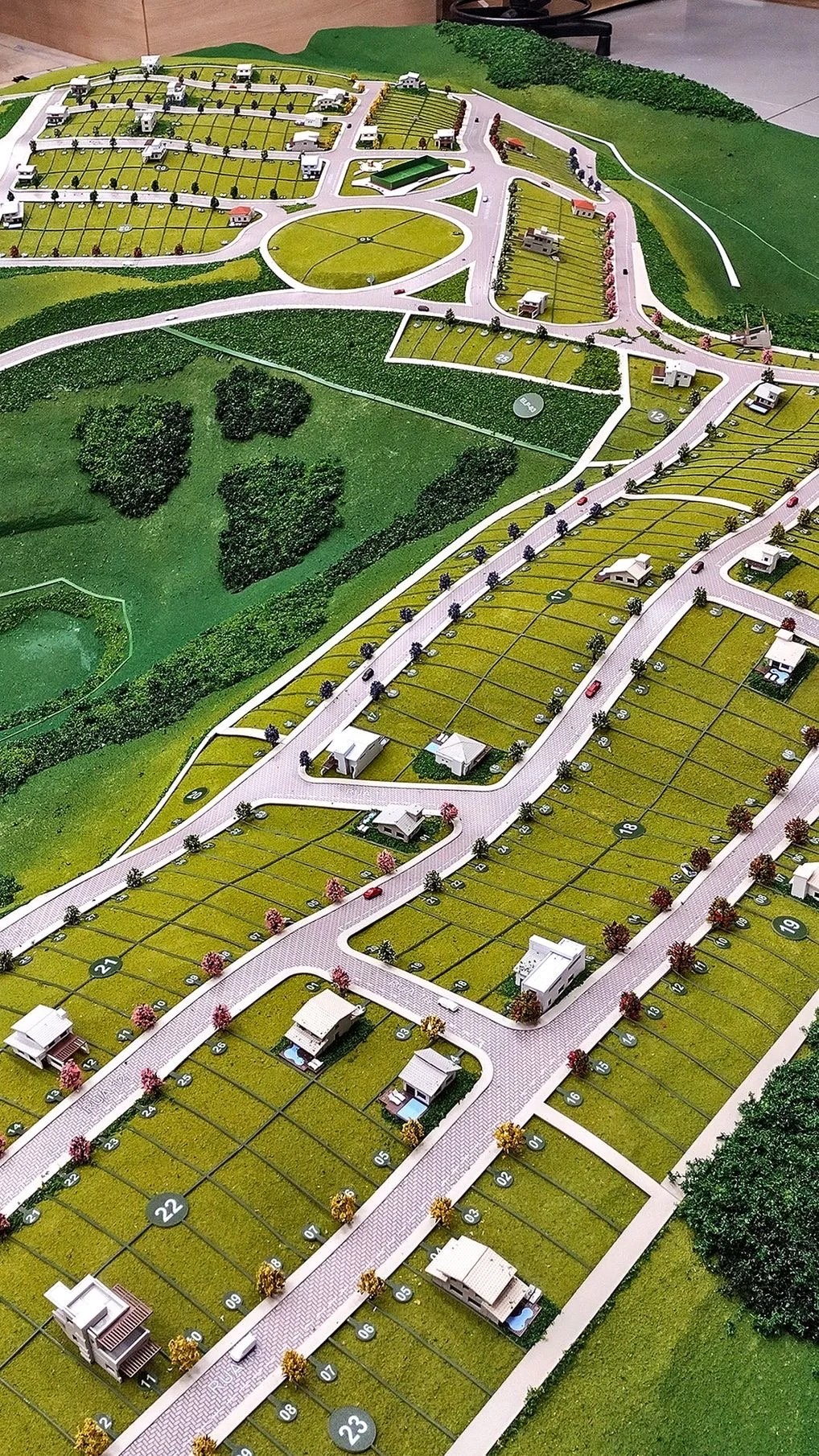 Model of a residential suburban neighborhood with numbered plots, streets, Trees, and small houses.