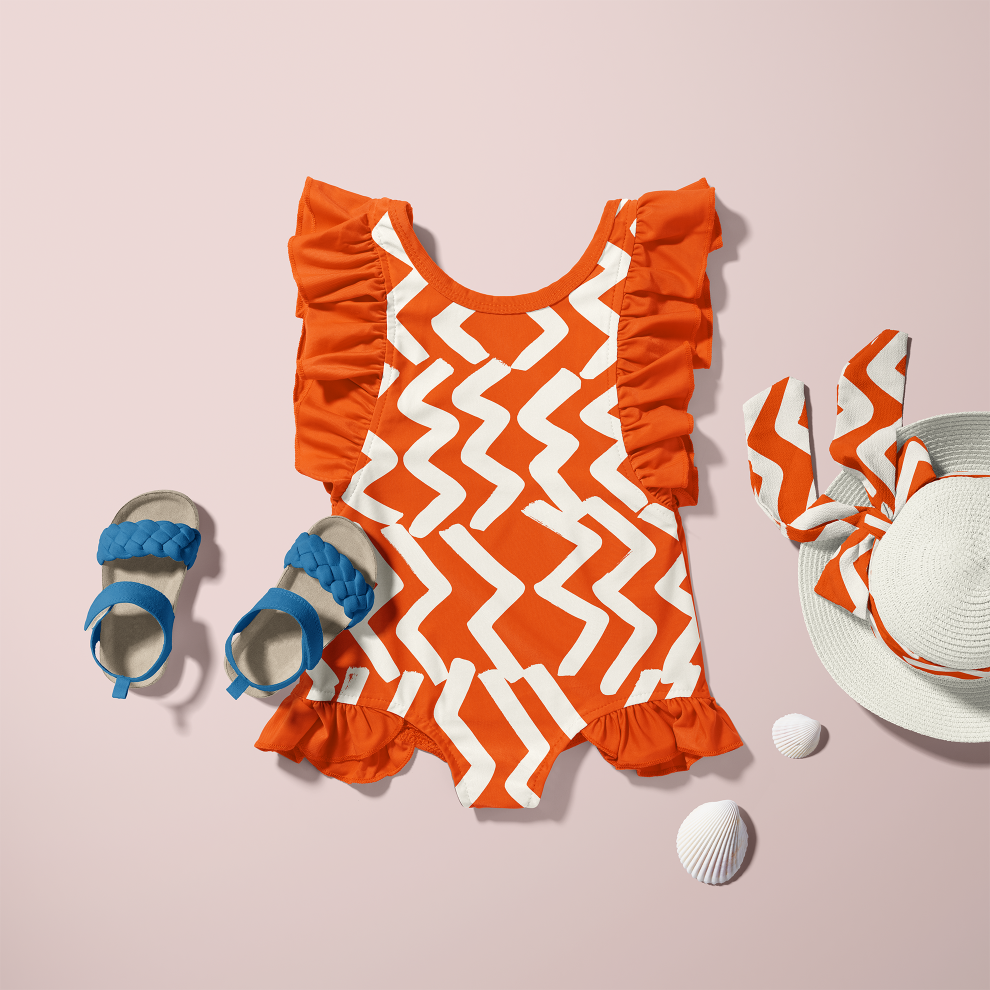 Orange and white zigzag patterned children's swimsuit with ruffled shoulders, design by Sarah Corynen.