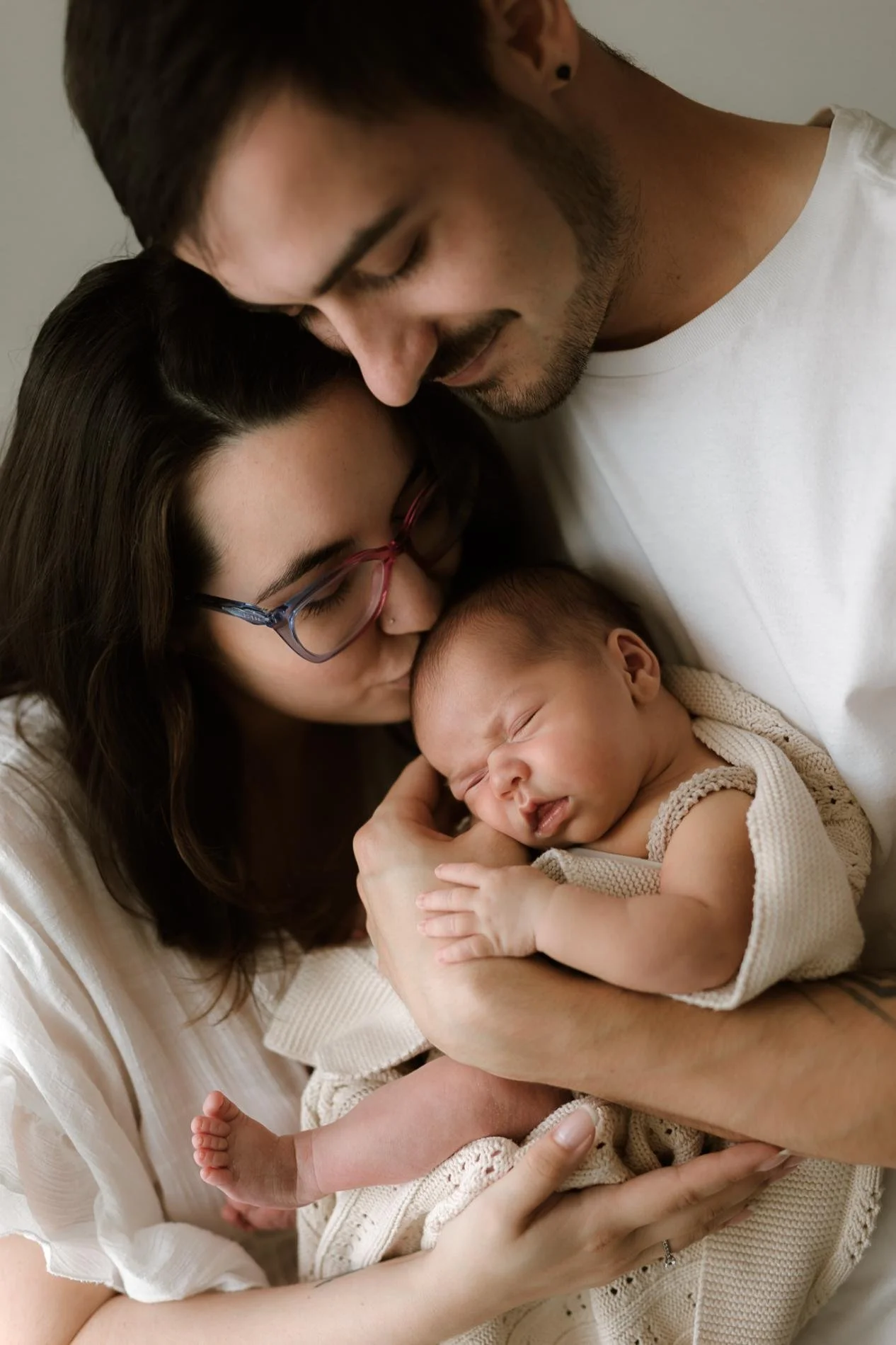 Polohované newborn focení - maminka s tatínkem drží své miminko v náručí