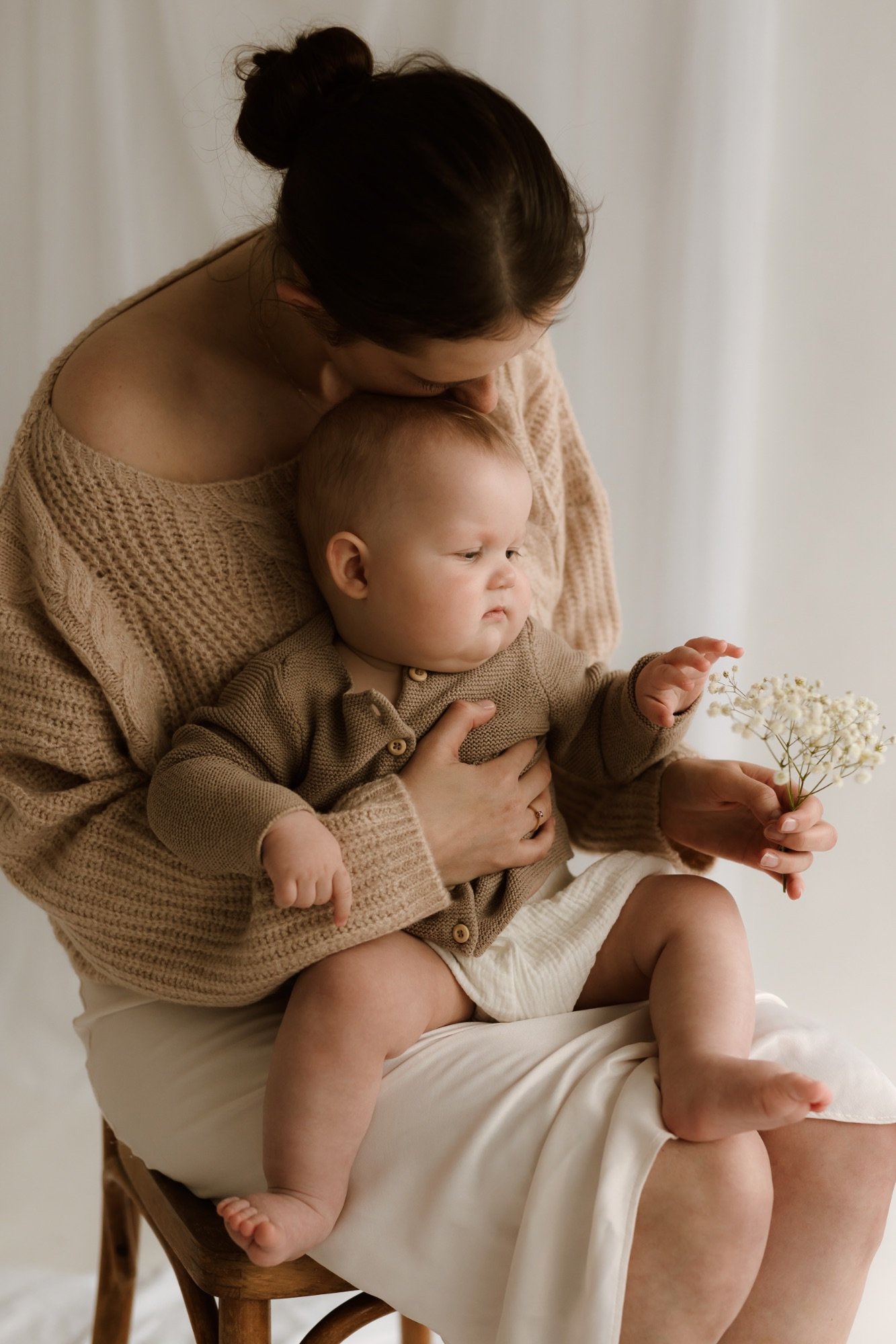 Maminka mazlí své dítě při mateřském focení v ateliéru