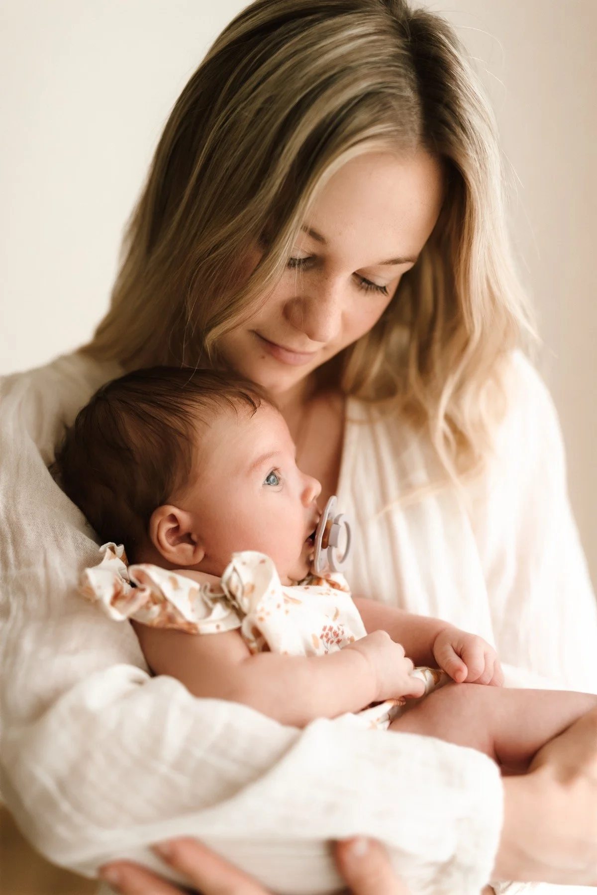 Newborn focení - maminka drží v náručí svou dceru při focení newborn