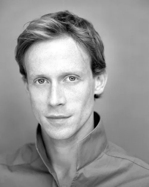 Black-and-white portrait of Edward Watson MBE, wearing a high-collared shirt, looking directly at the camera.