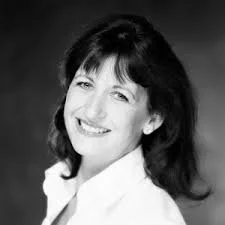 Black and white portrait of a smiling woman with shoulder-length hair wearing a light-colored top.