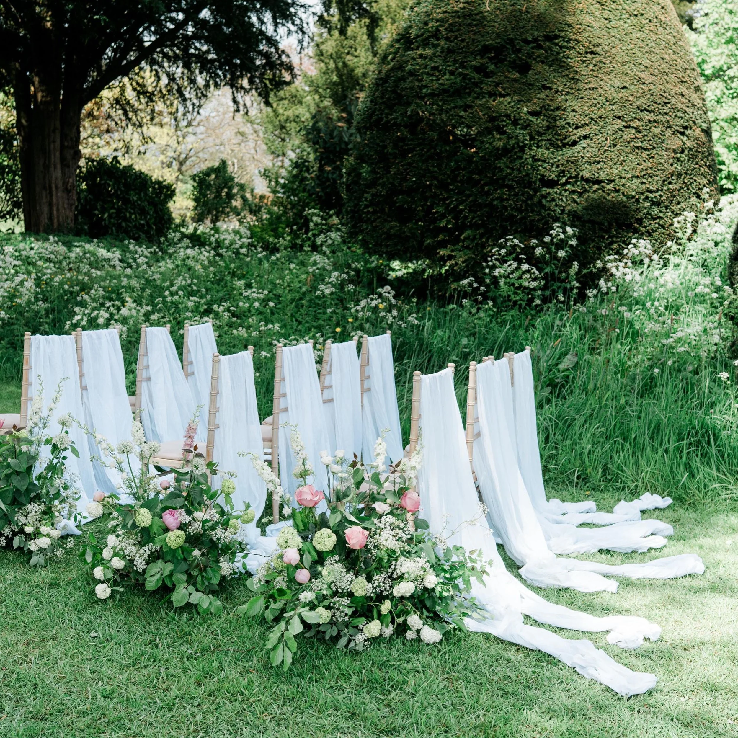 Softly draped fabric, flowers spilling gently into the aisle, and a ceremony setting designed to feel as though it had simply grown into the garden.
Relaxed, romantic, and a little undone in the most beautiful way.

Photography @jennyjonesphotography